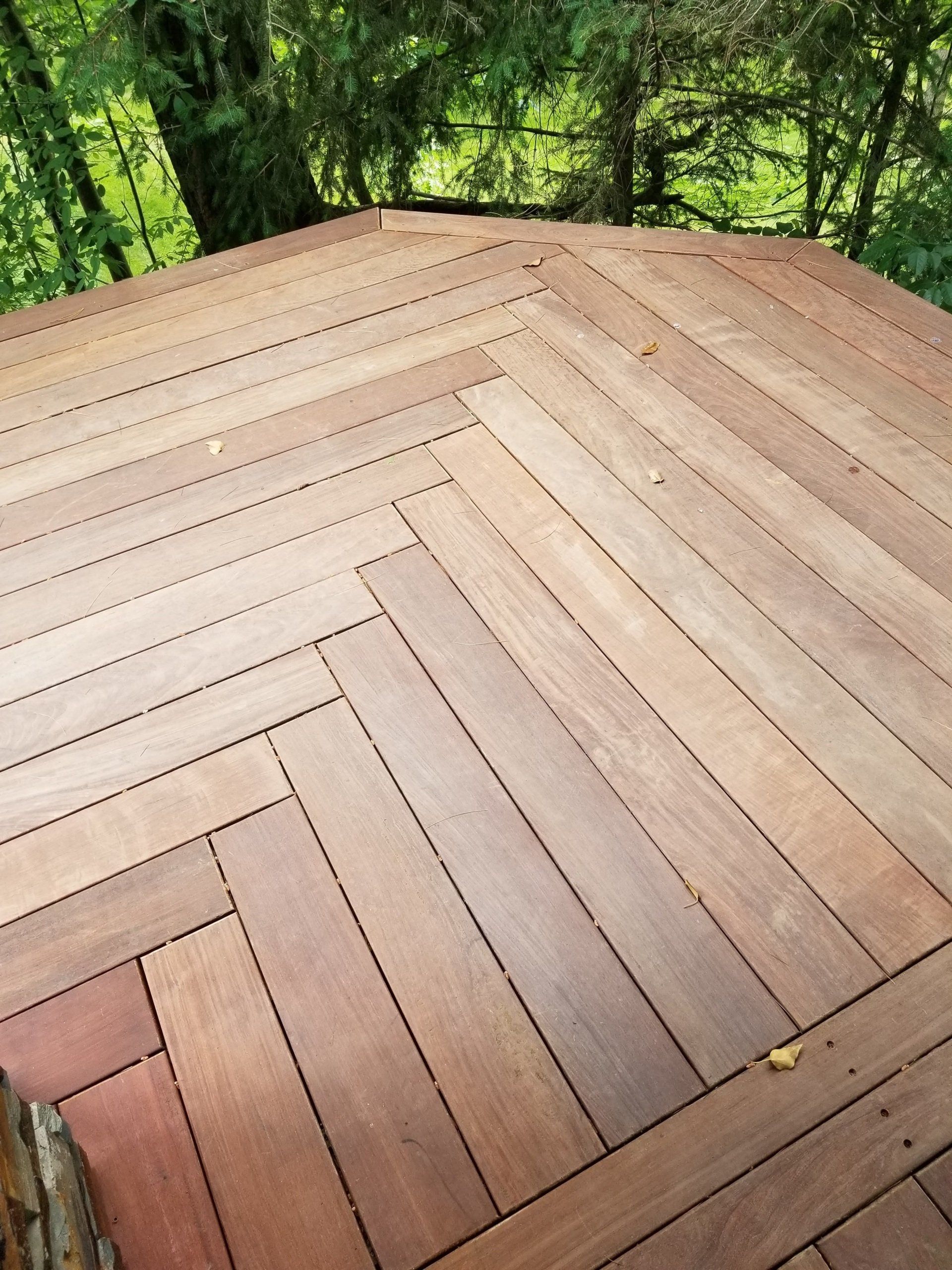 A wooden deck with a table and bench under a pergola.