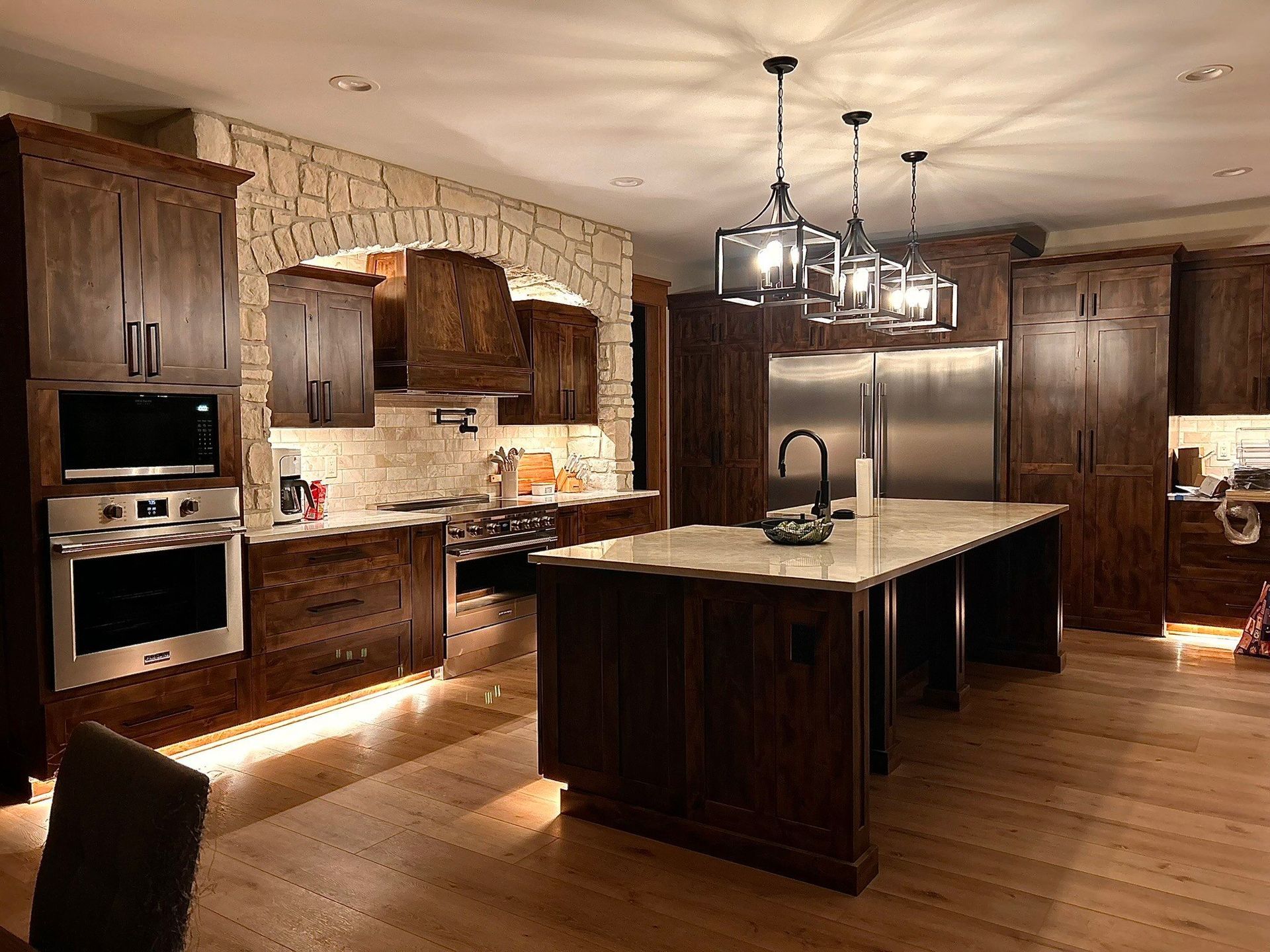 A kitchen with stainless steel appliances , wooden cabinets , and a large island.