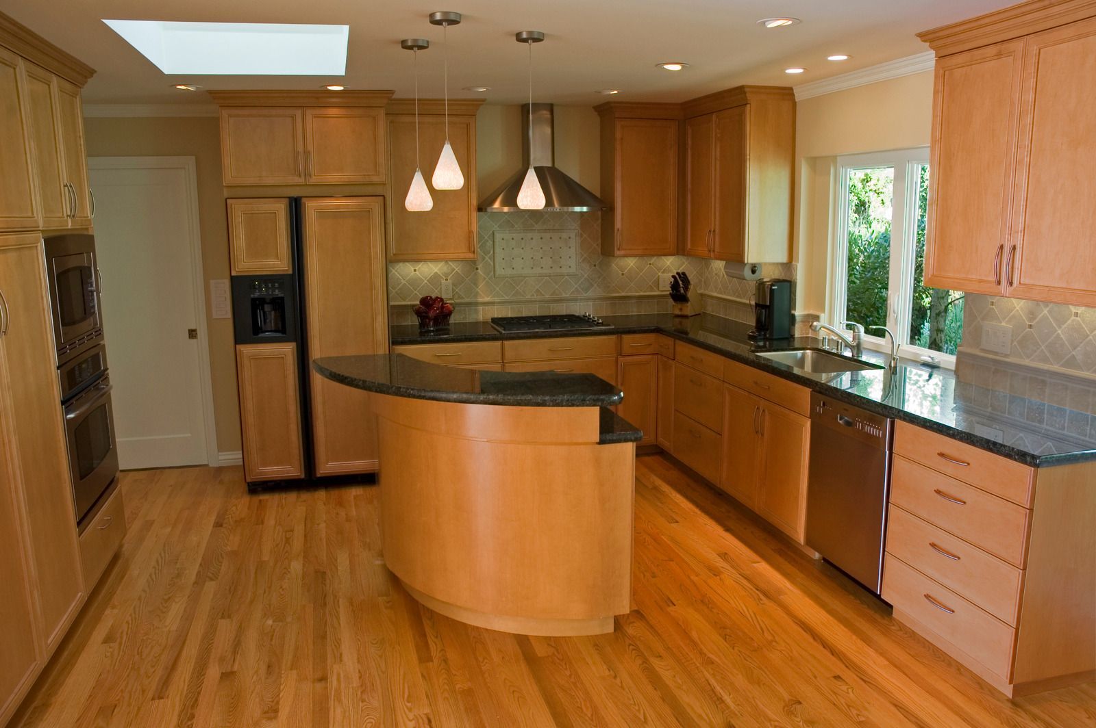 A kitchen with wooden cabinets , granite counter tops , and stainless steel appliances.