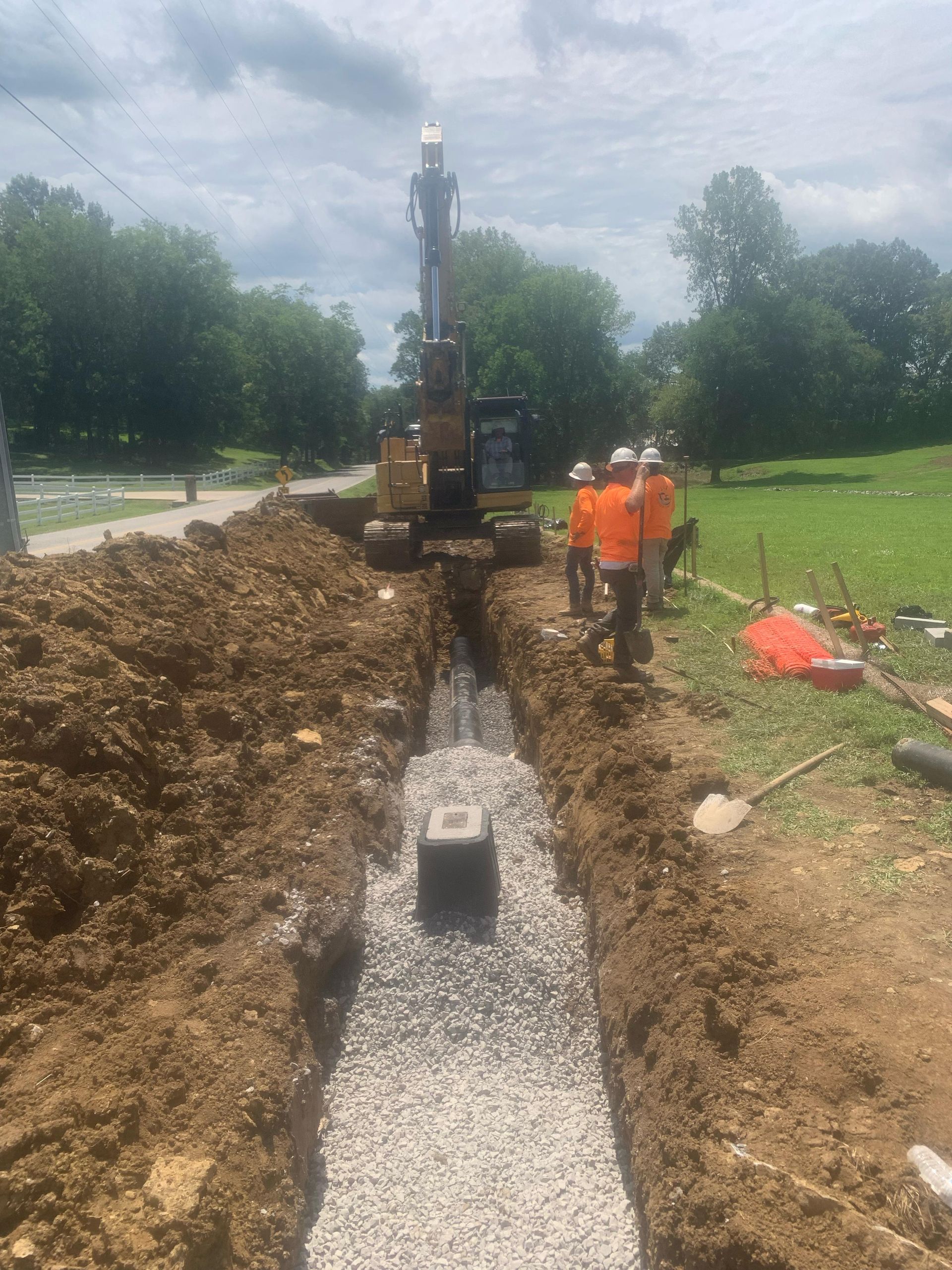 A group of construction workers are digging a trench in the dirt.