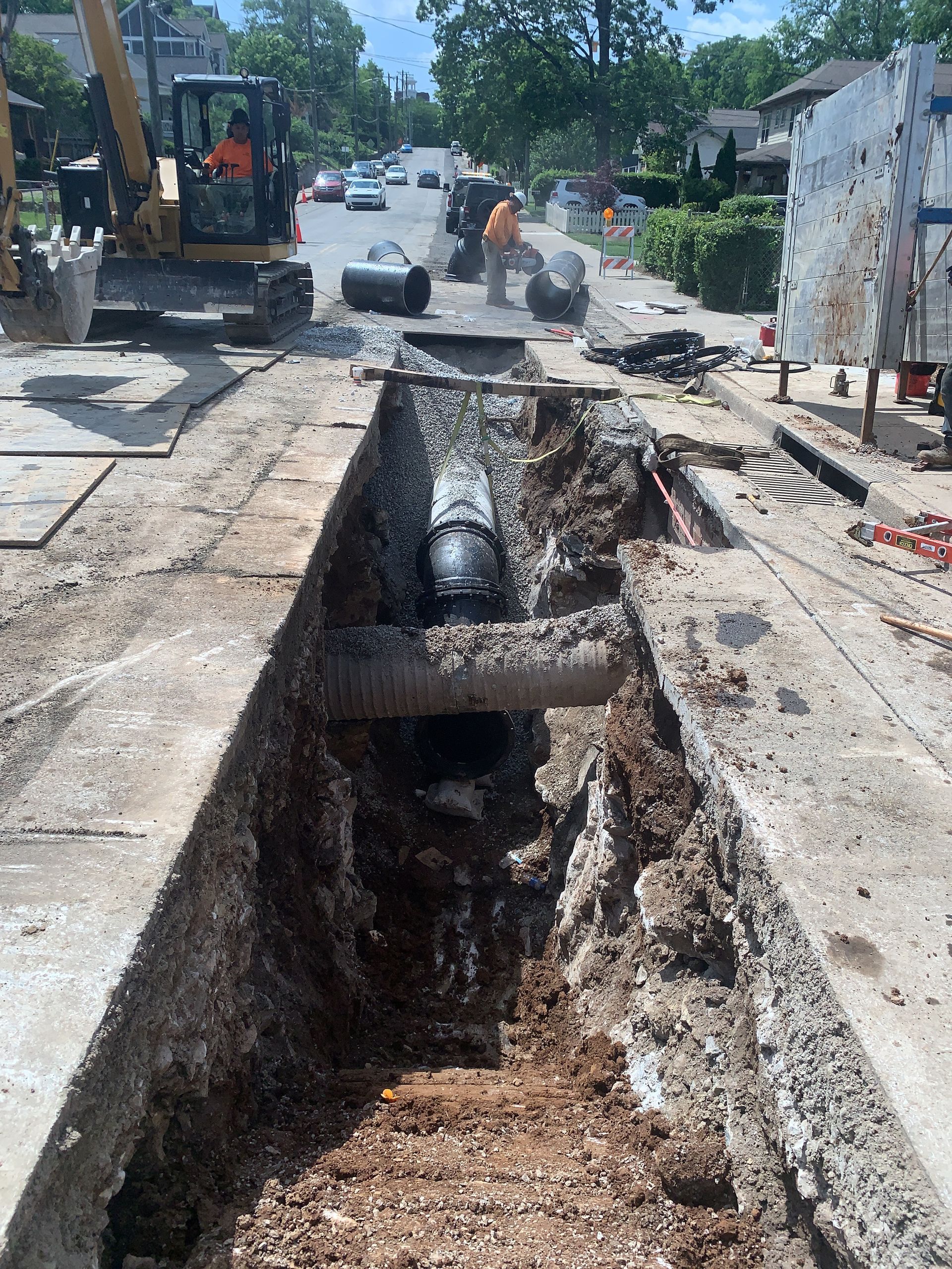 A pipe is being installed in a trench on the side of the road.