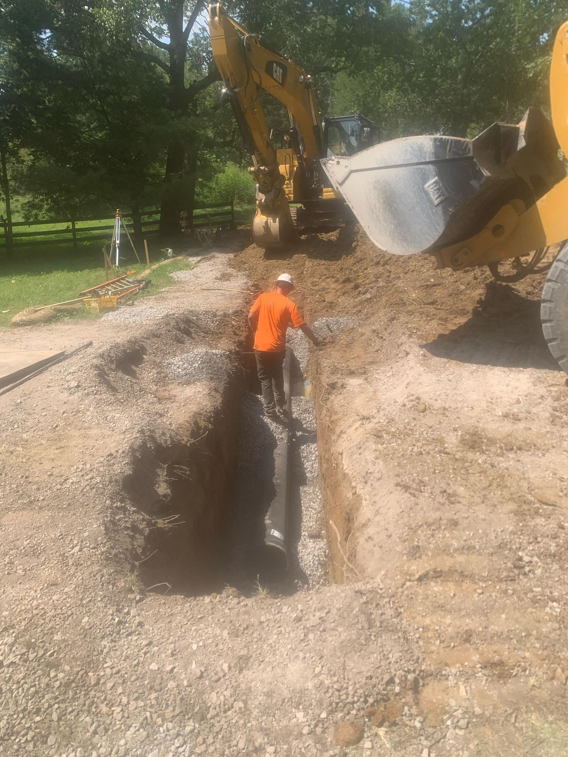A man is digging a hole in the ground next to a bulldozer.