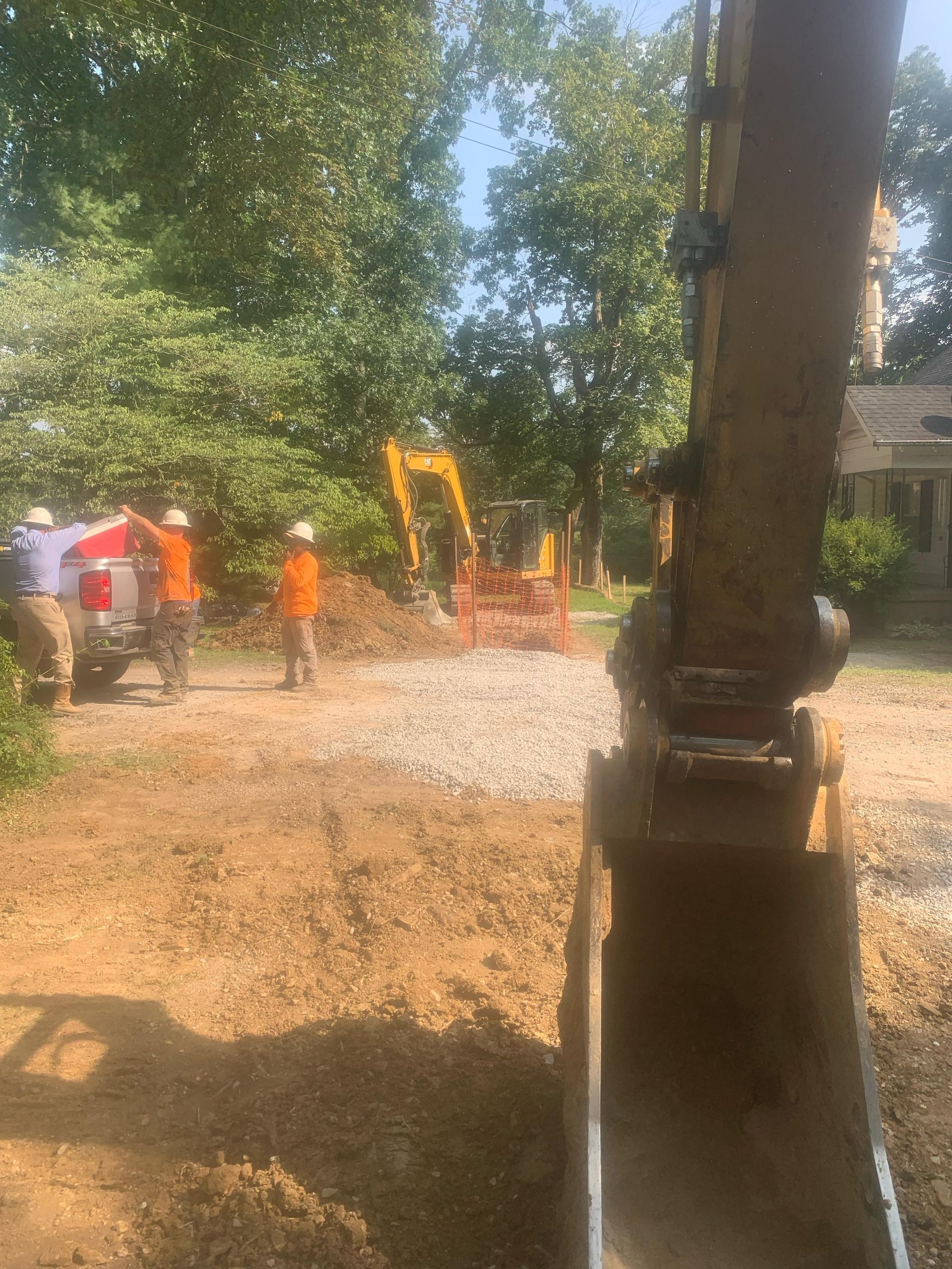 A group of construction workers are working on a dirt road.