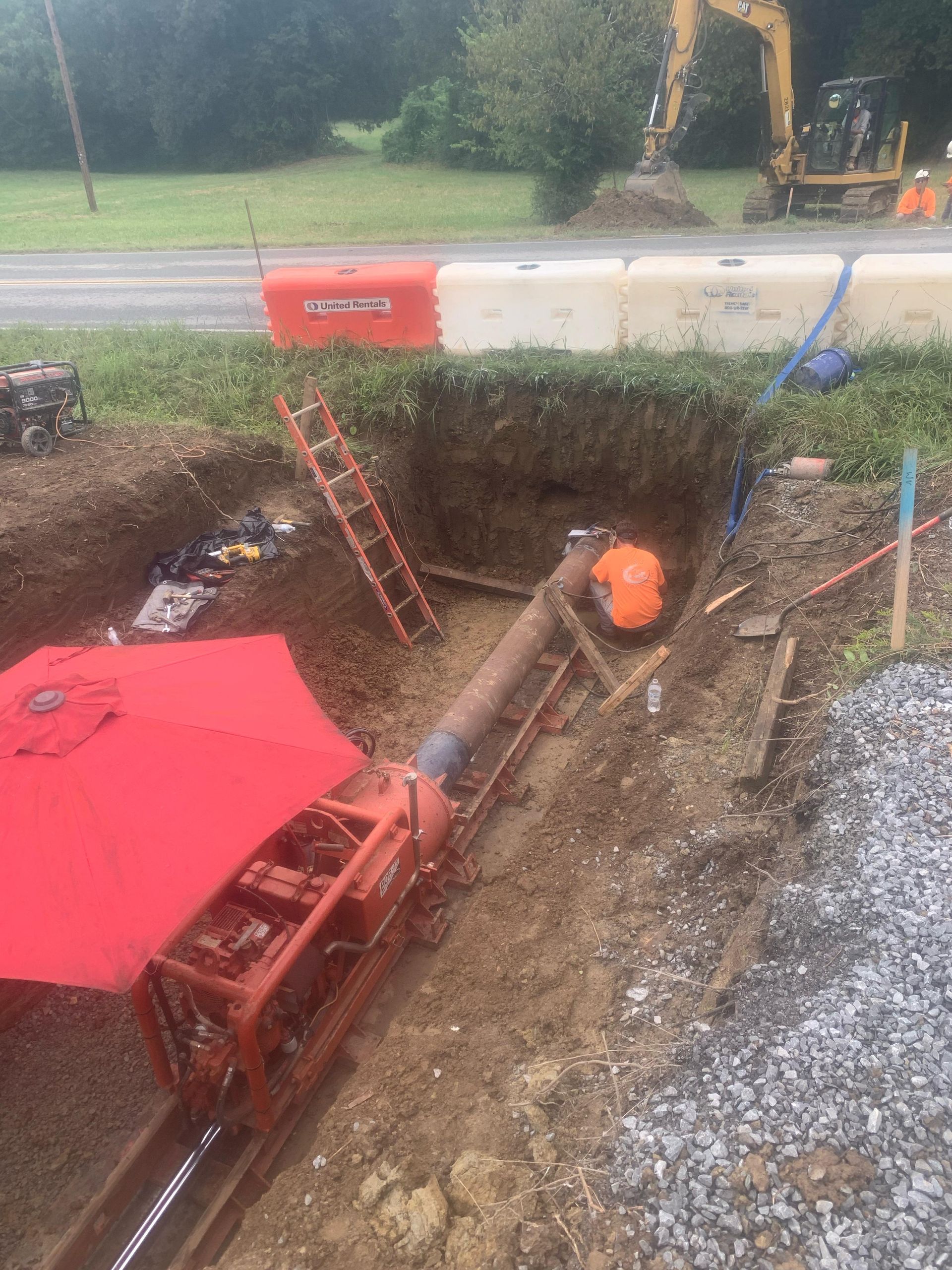 A man is working on a pipe in a hole in the ground.