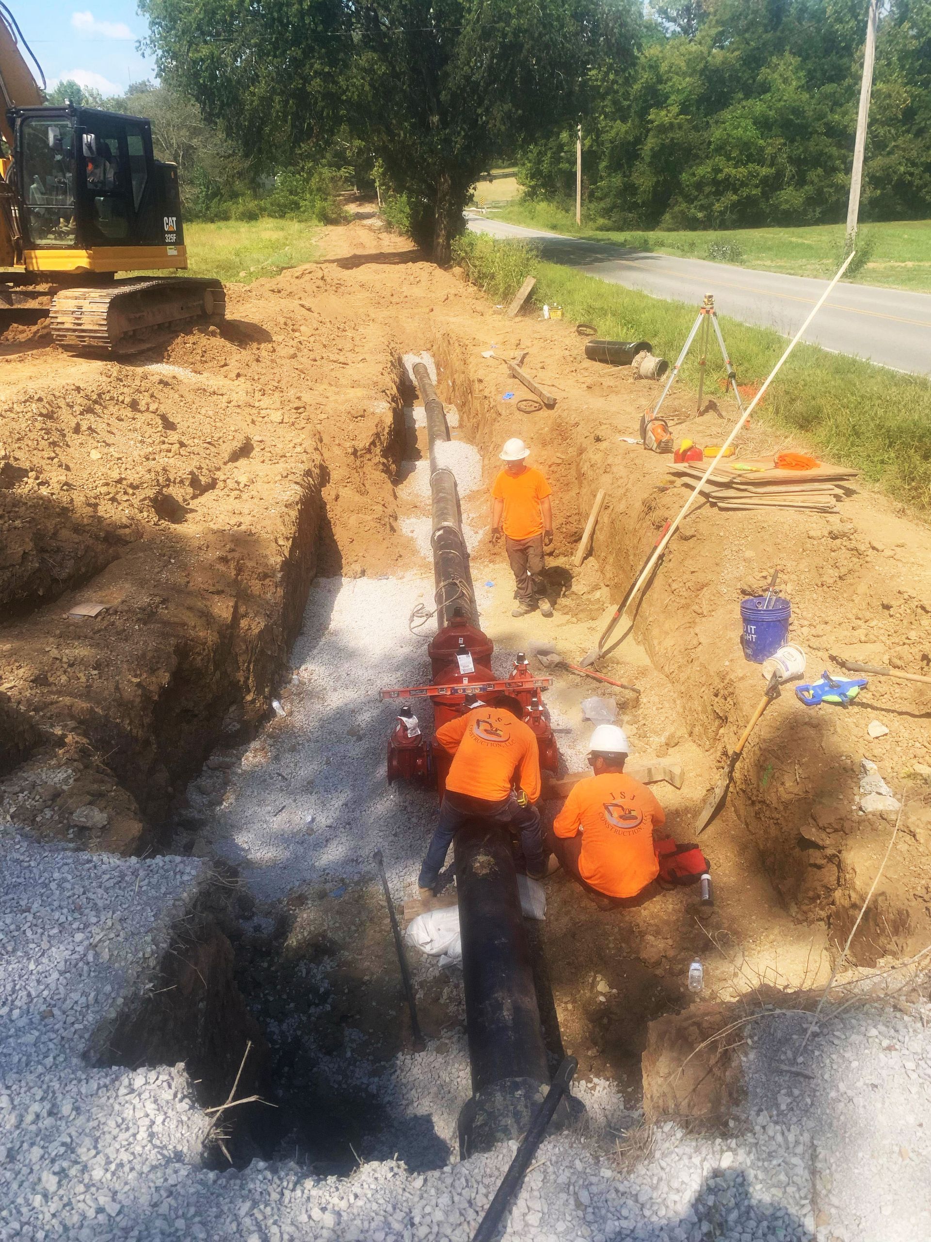 A group of construction workers are working on a pipe in the dirt.