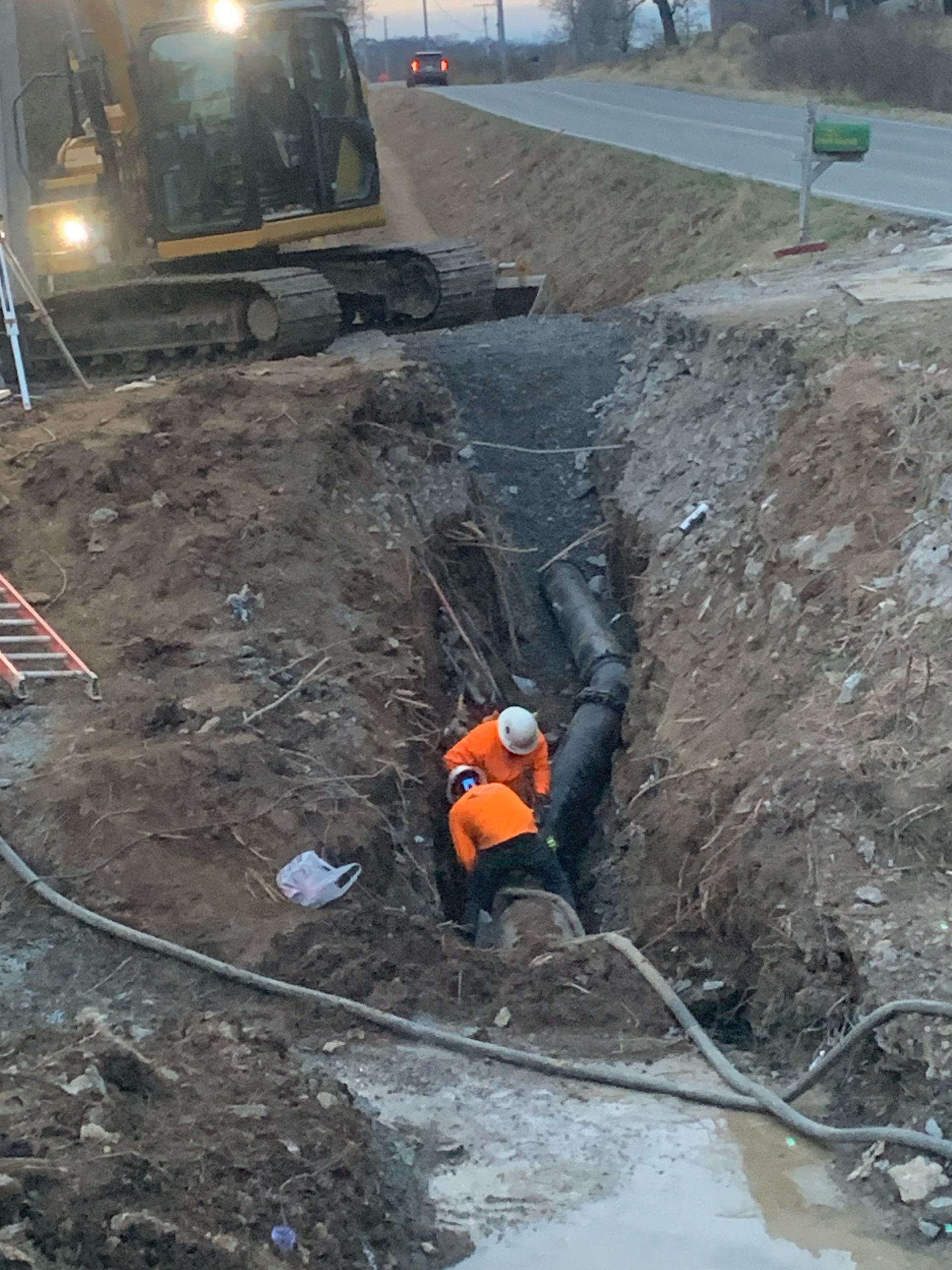 A group of construction workers are working on a pipe in the dirt.