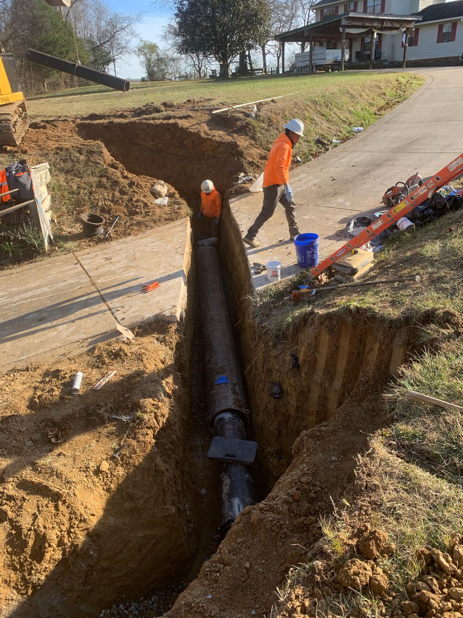 A man is standing next to a pipe in the dirt.
