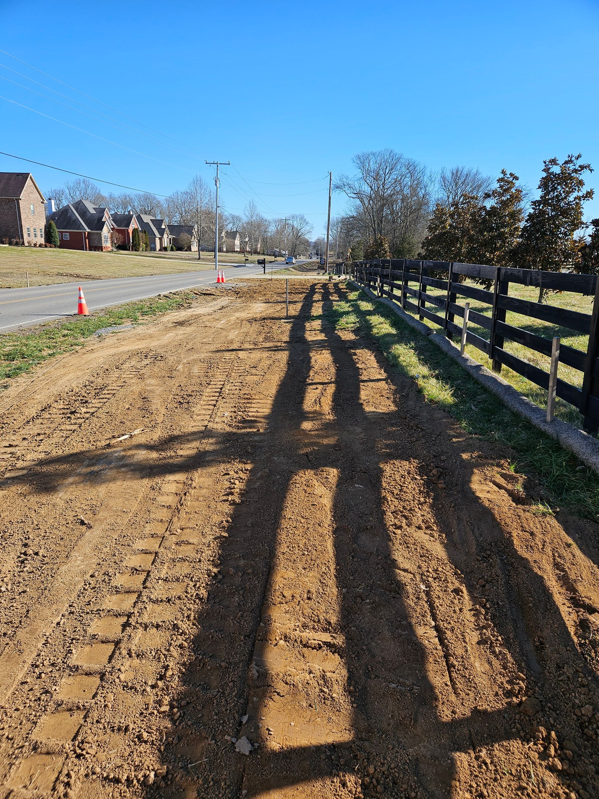 A dirt road with a wooden fence along the side of it.