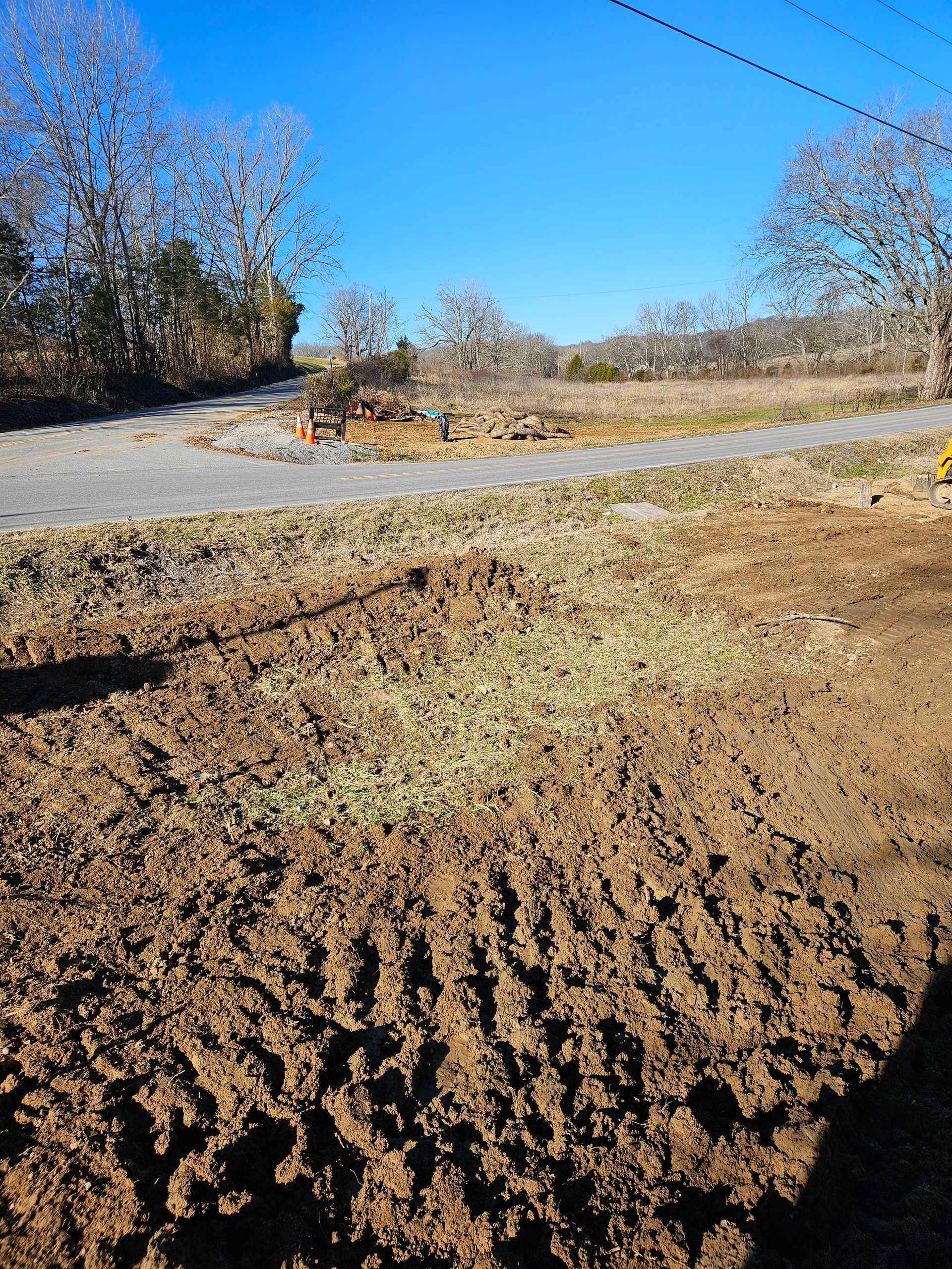 A muddy field with a road and trees in the background