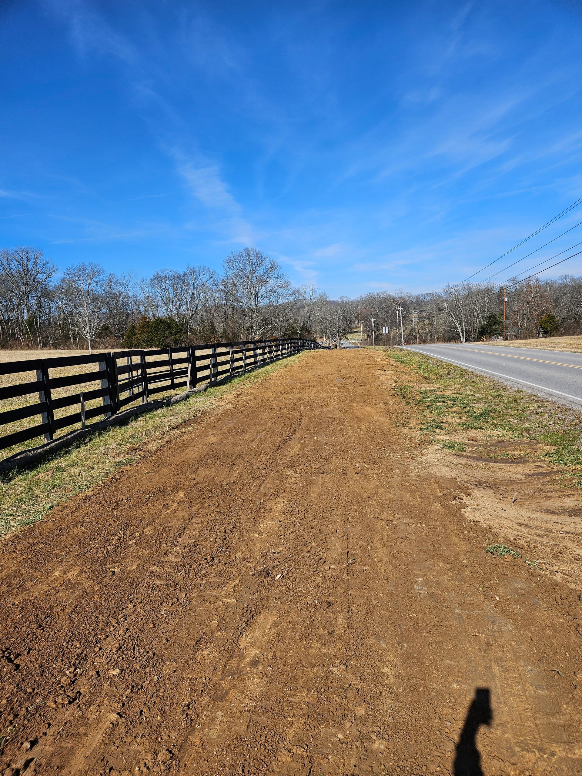 A dirt road with a wooden fence along the side of it.