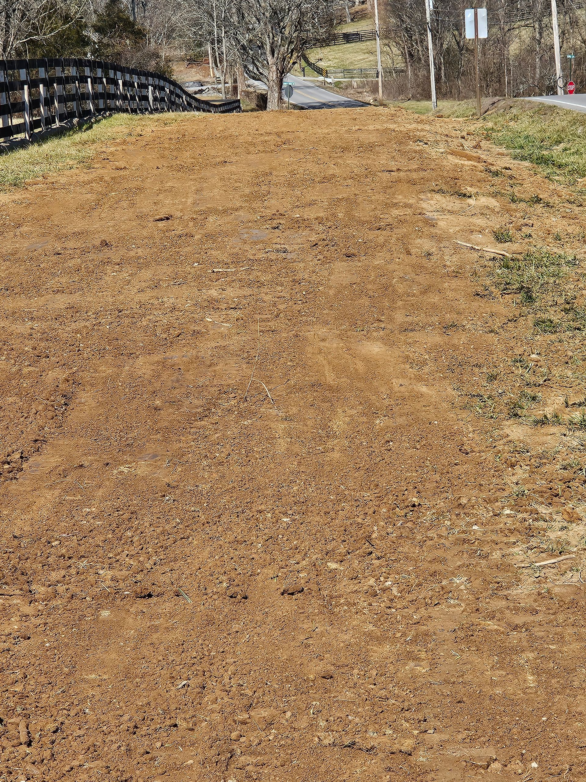 A dirt field with a fence in the background.