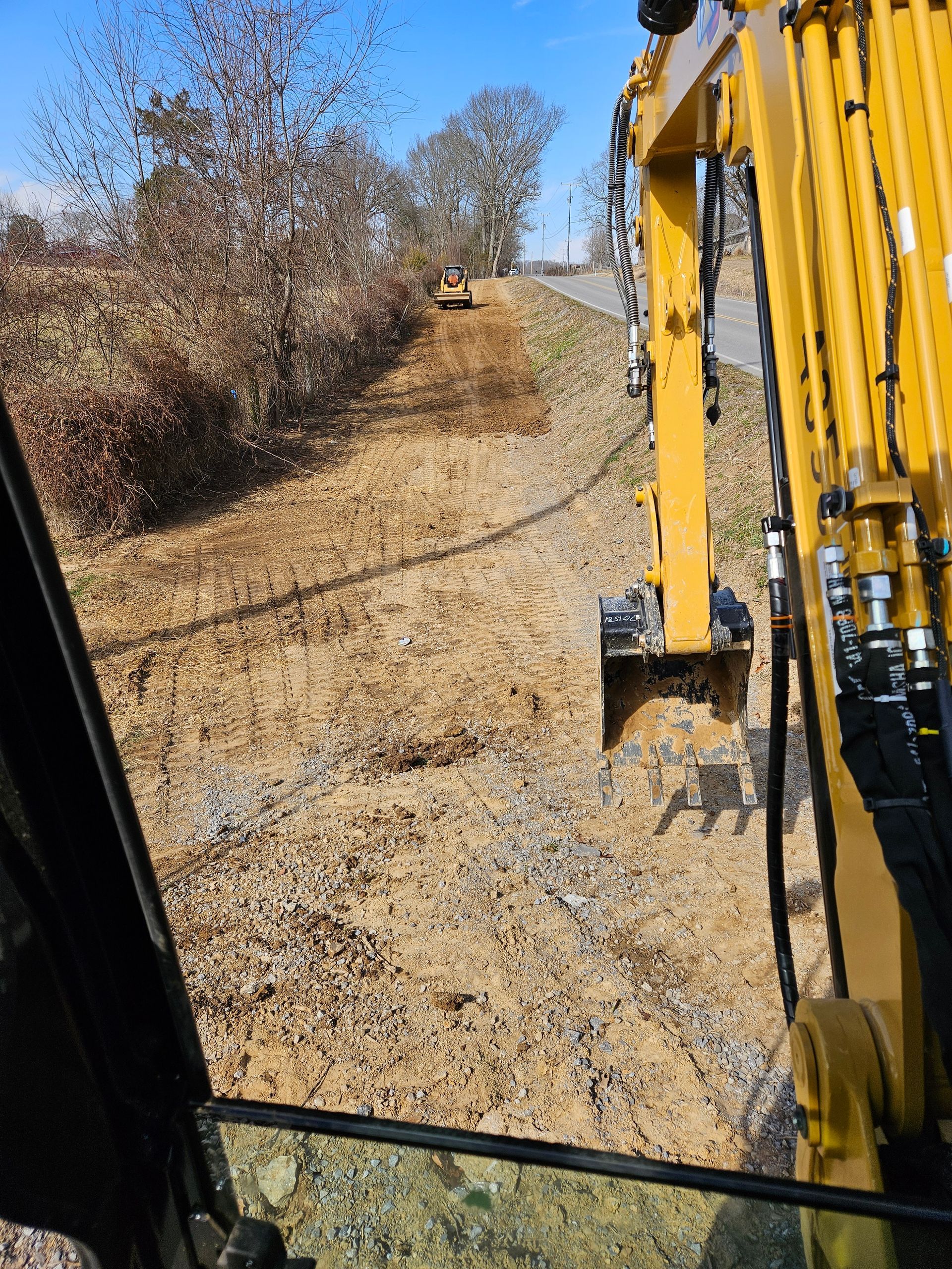 A yellow excavator is working on a dirt road.