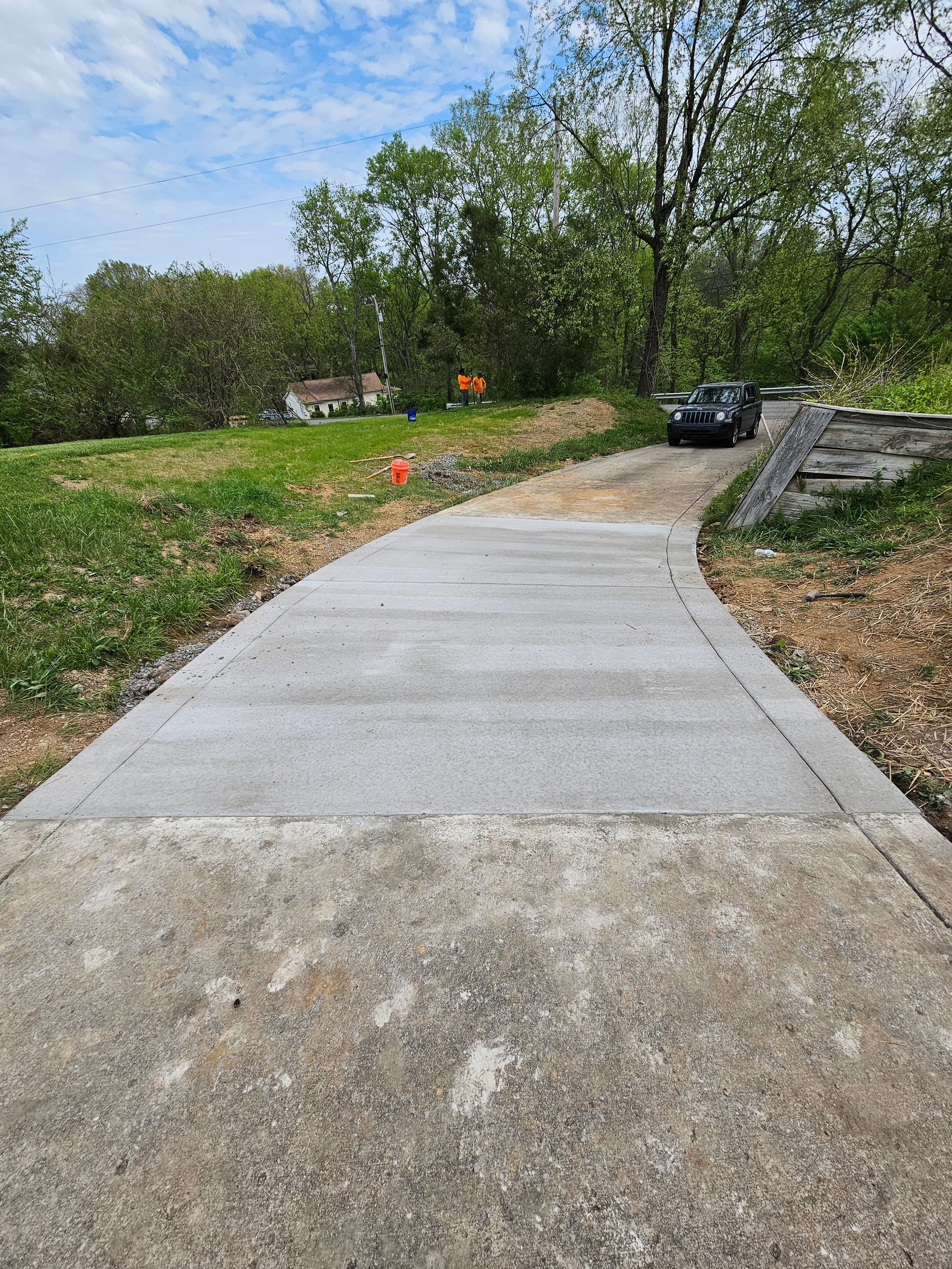 A concrete driveway with a car parked on the side of it.