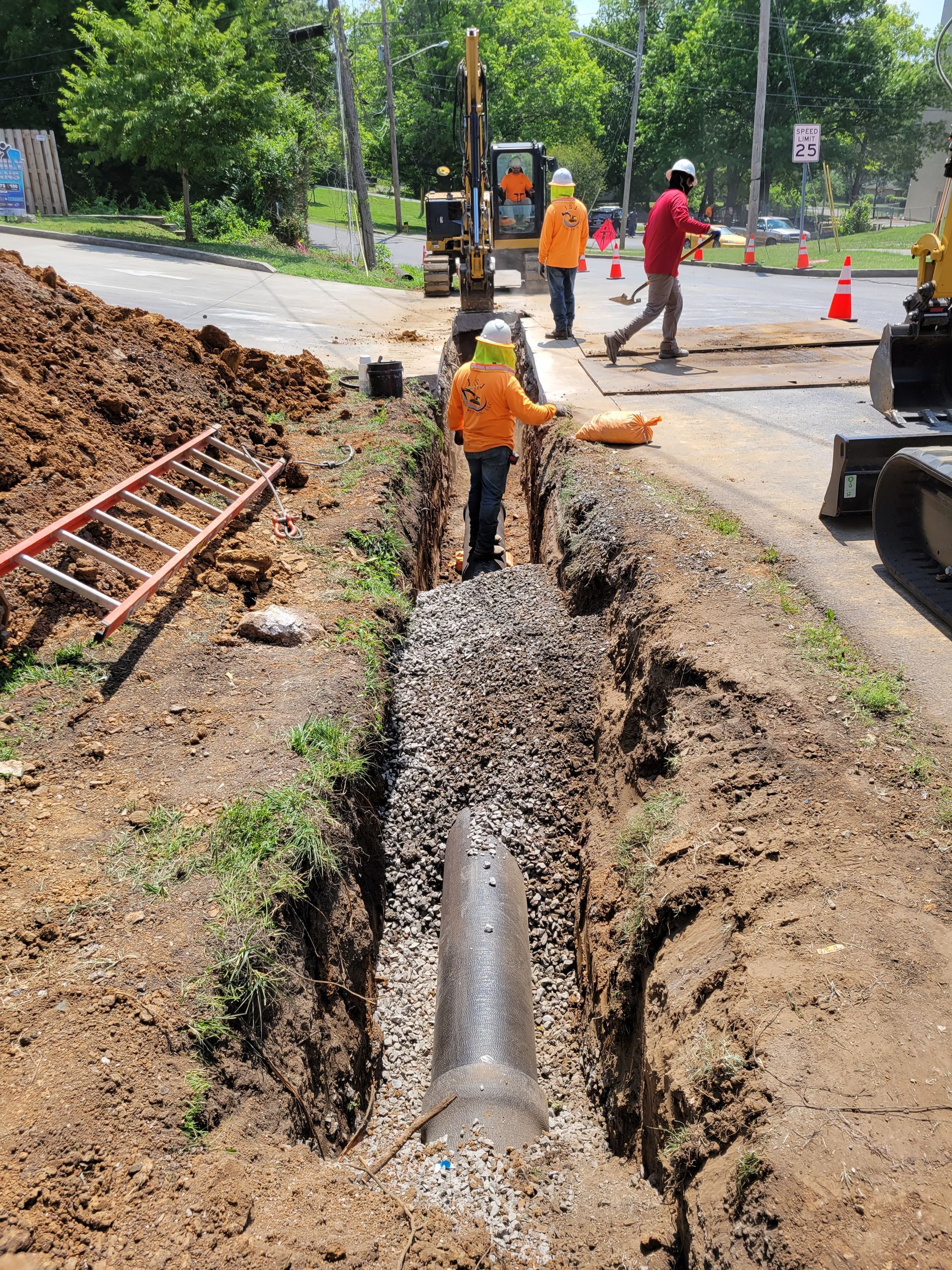 A group of construction workers are working on a pipe in the dirt.
