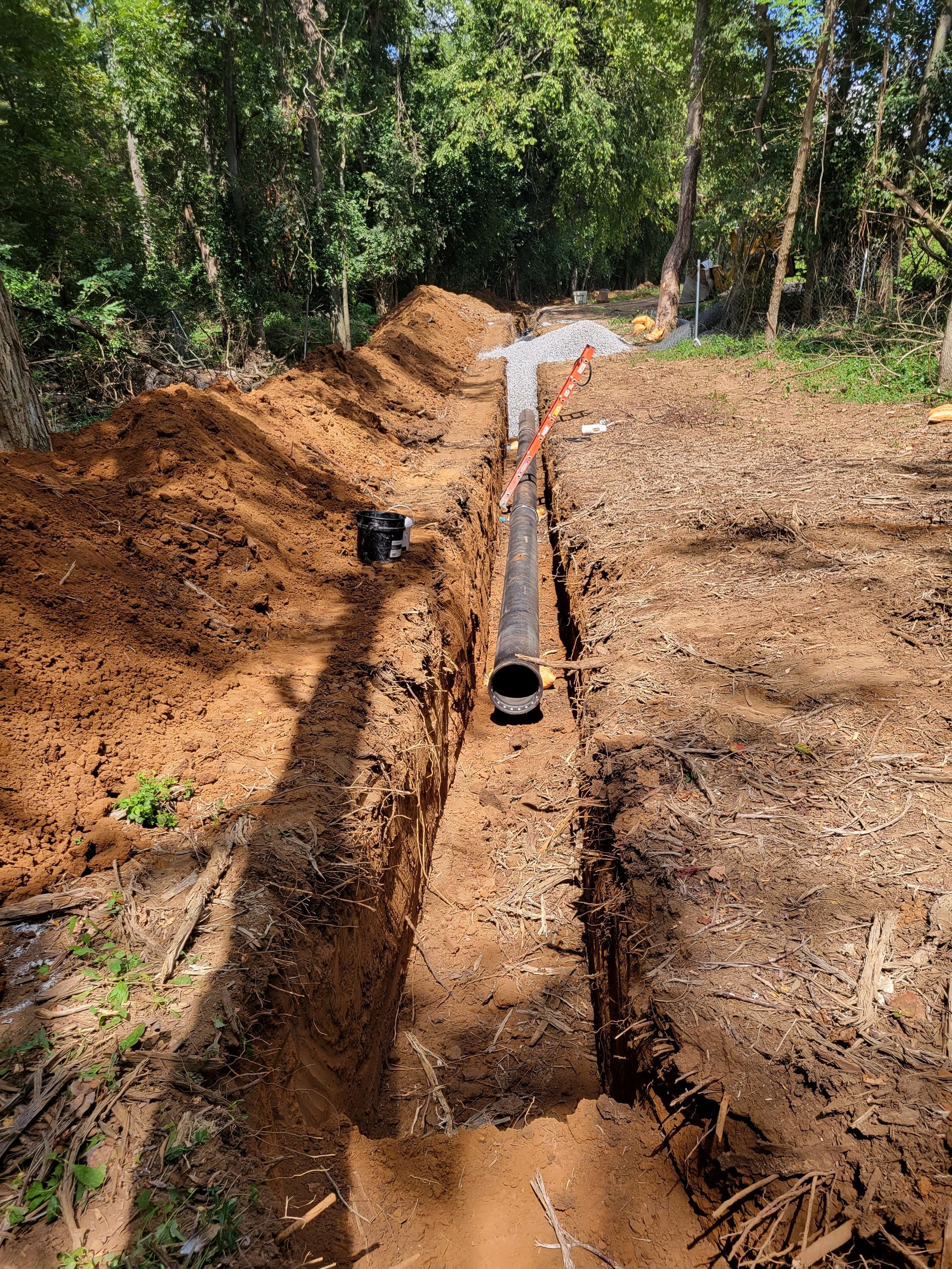 A pipe is being installed in a trench in the dirt.