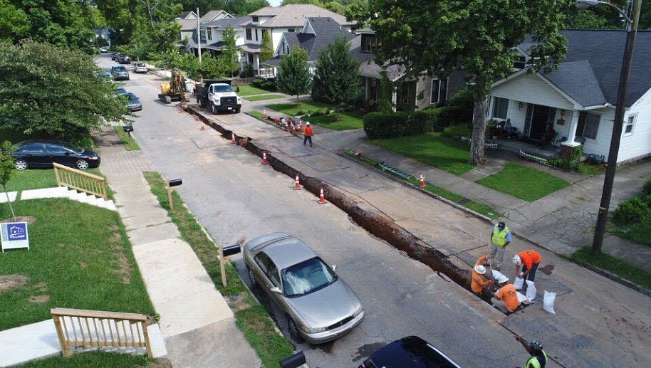 An aerial view of a residential street with a car parked on the side of the road.