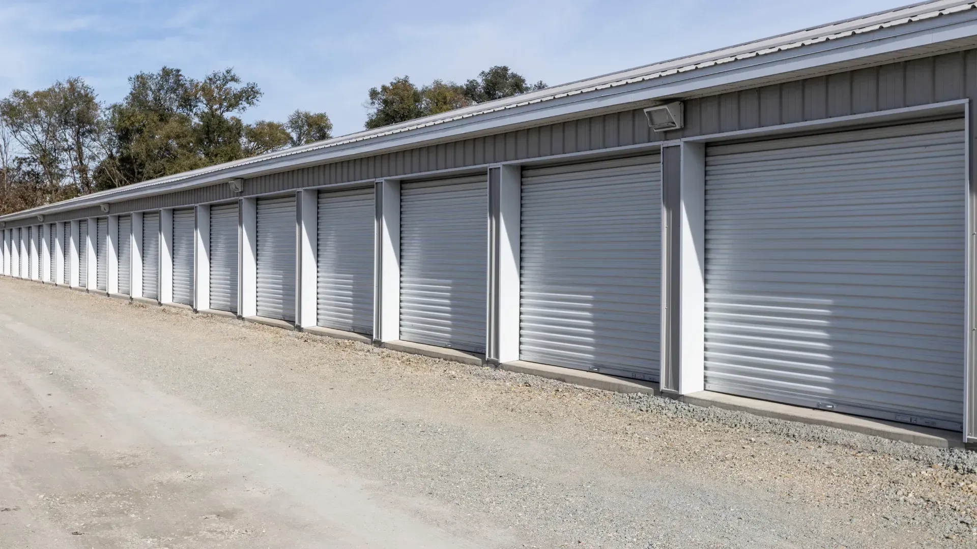 A row of garage doors are lined up next to each other on a gravel road.