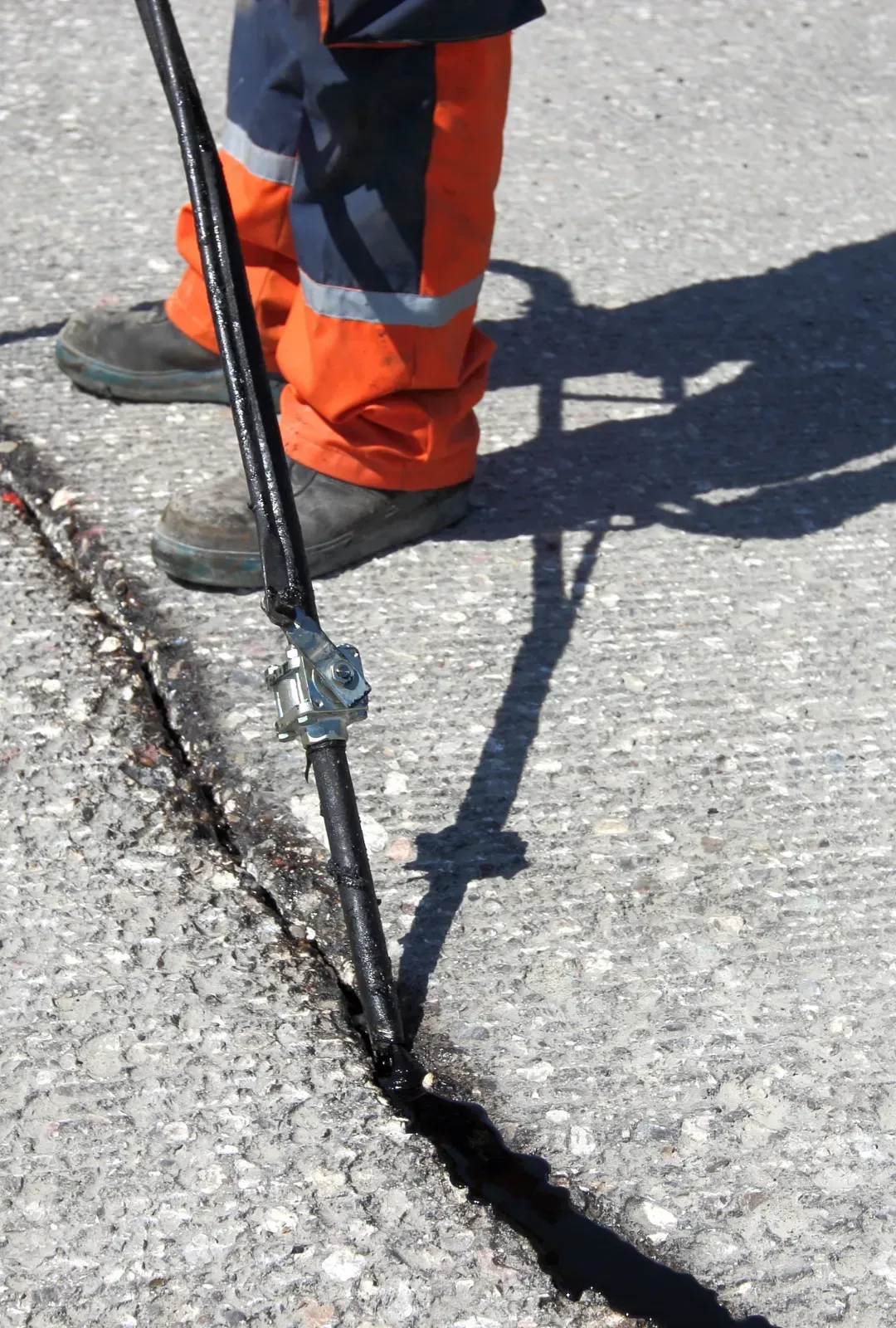 A person is standing on a concrete surface with a stick in their hand