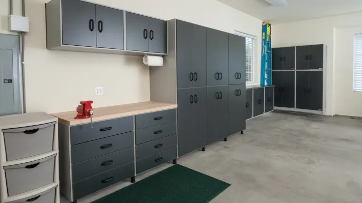 A garage with lots of cabinets and drawers and a green rug.