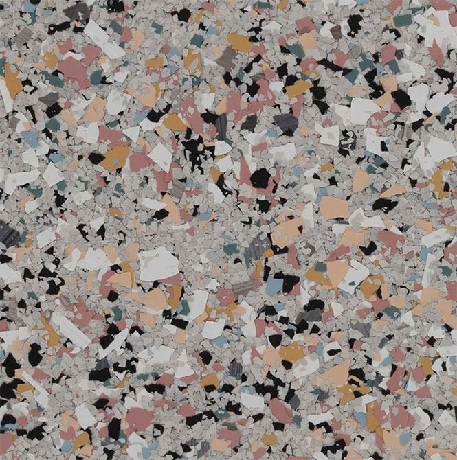 Terrazzo-style flooring with various color chips on a gray background: pink, black, white, yellow, and blue.