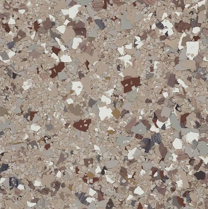 Close-up of a speckled floor coating in beige, brown, white, and gray chips.