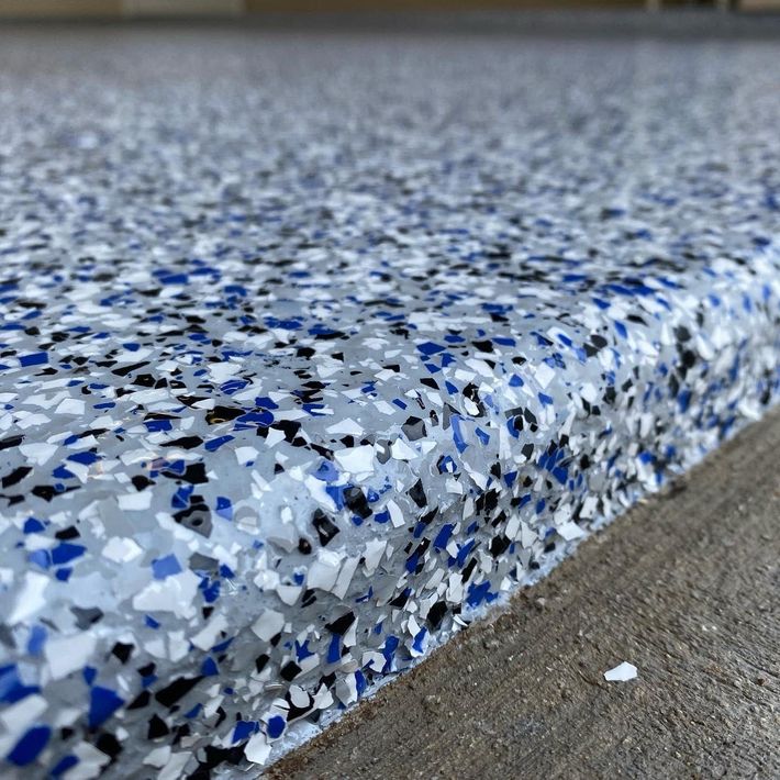 A paint roller is sitting on a concrete floor.