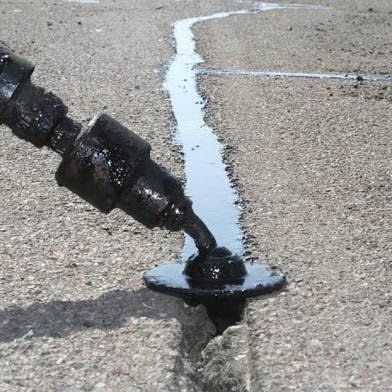 A person is standing on the side of the road holding a tool.