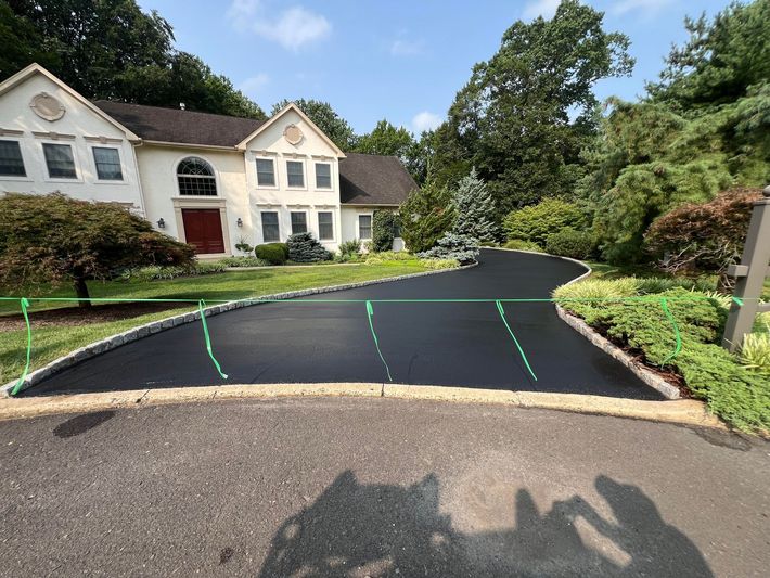 A black asphalt driveway next to a white garage door.