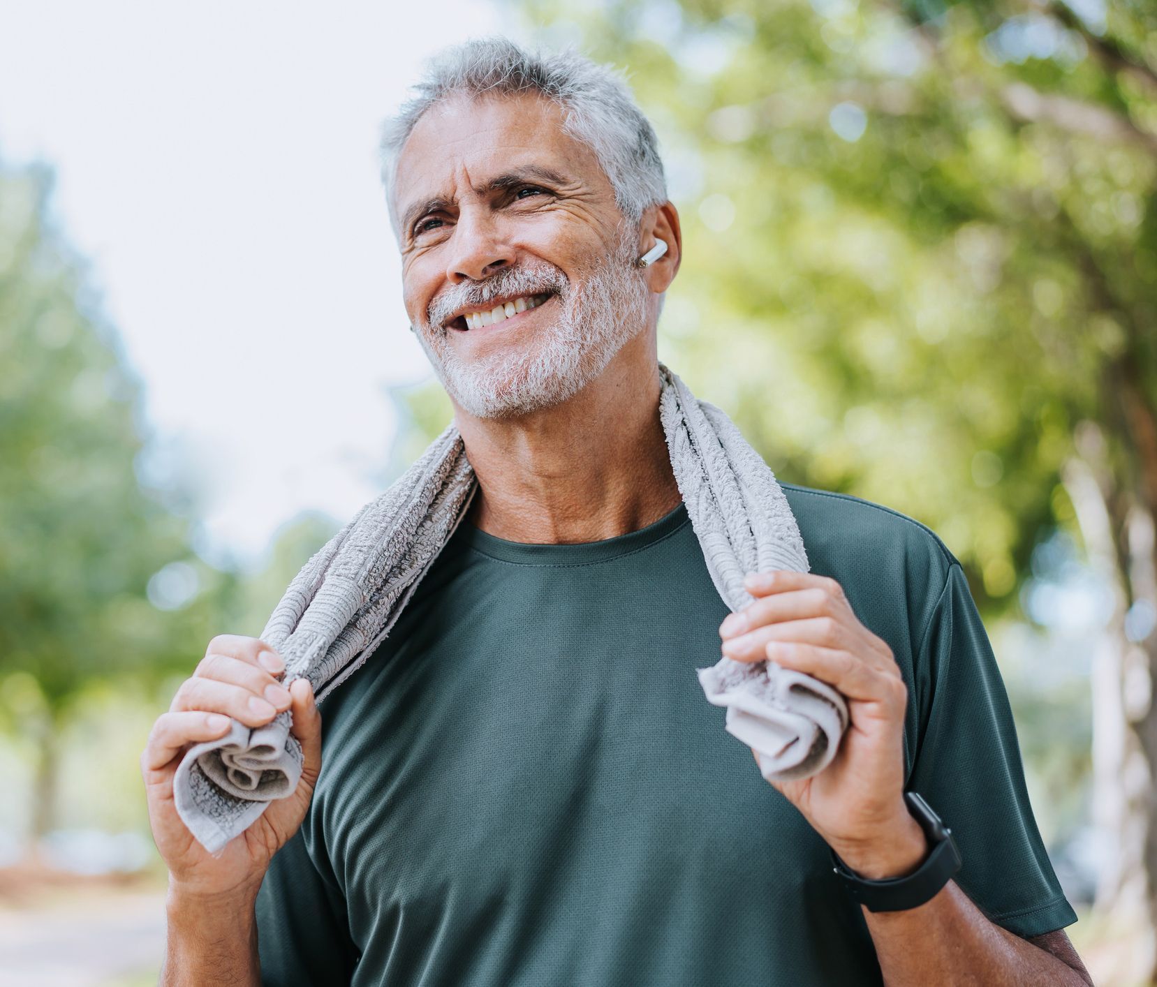 A man with a towel around his neck is smiling.