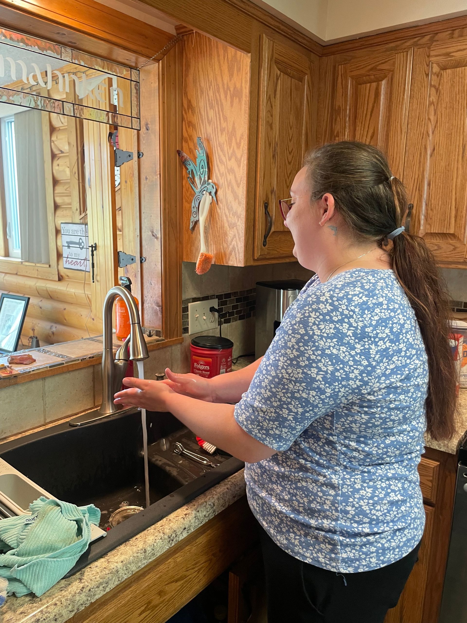 A woman is washing her hands in a kitchen sink.