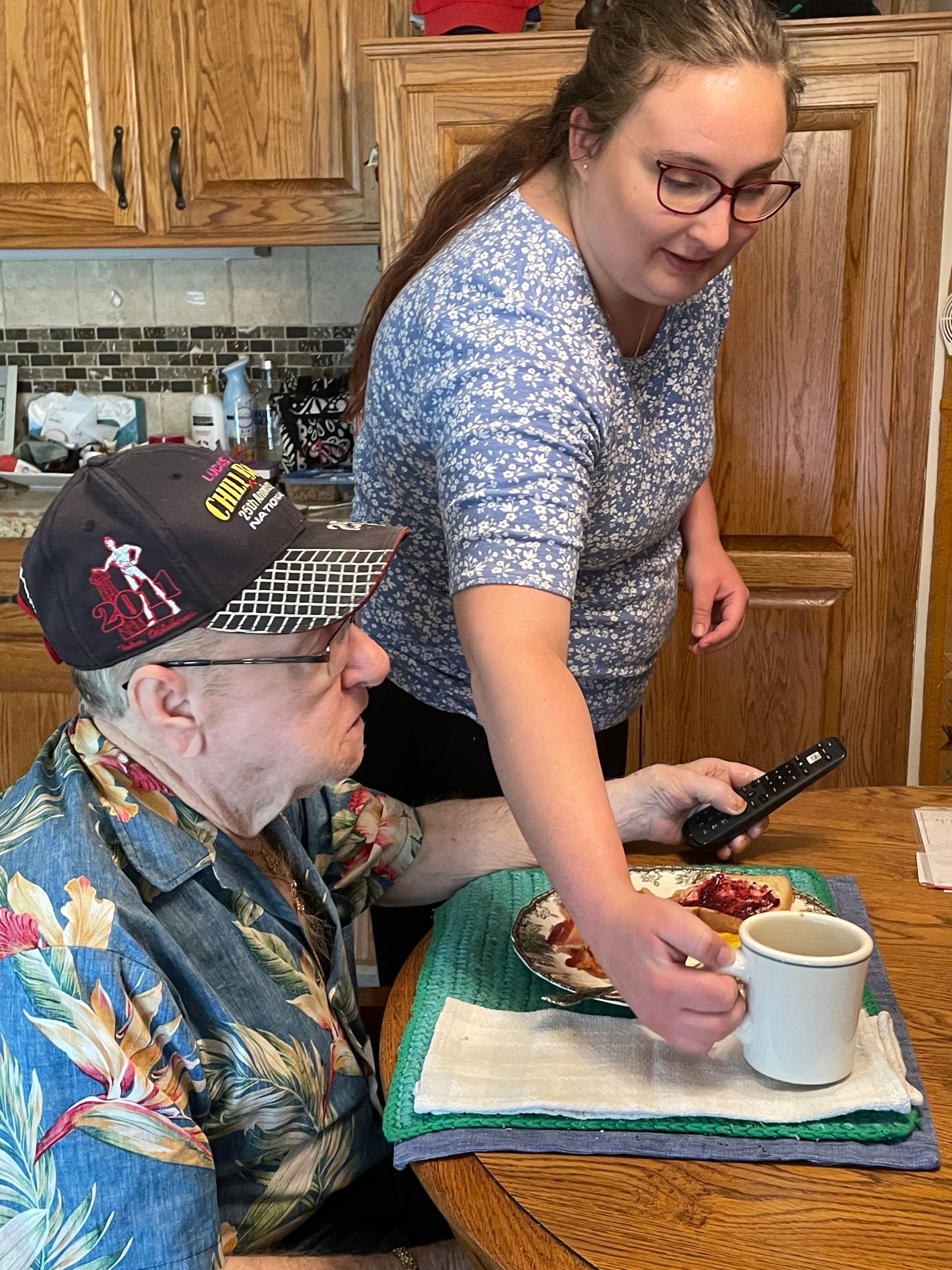 A woman is standing next to a man at a table.