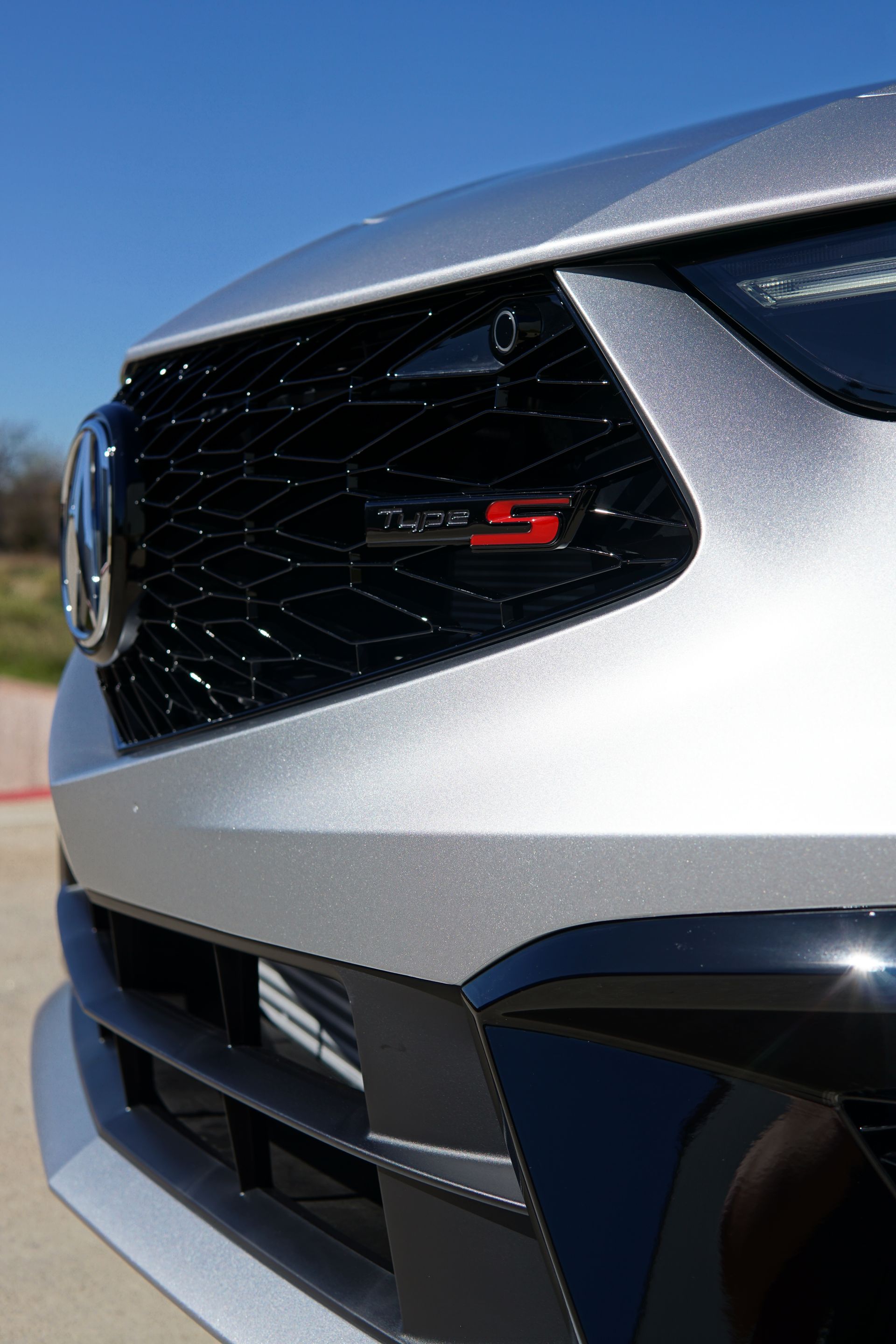 A close up of the front of a silver car with a black grill.