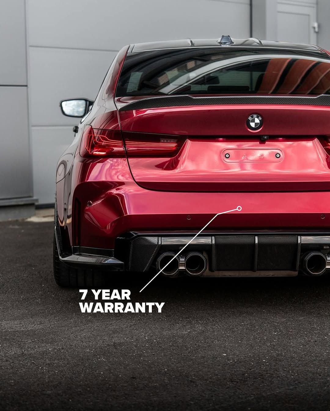 A red bmw with a 7 year warranty is parked in front of a building.