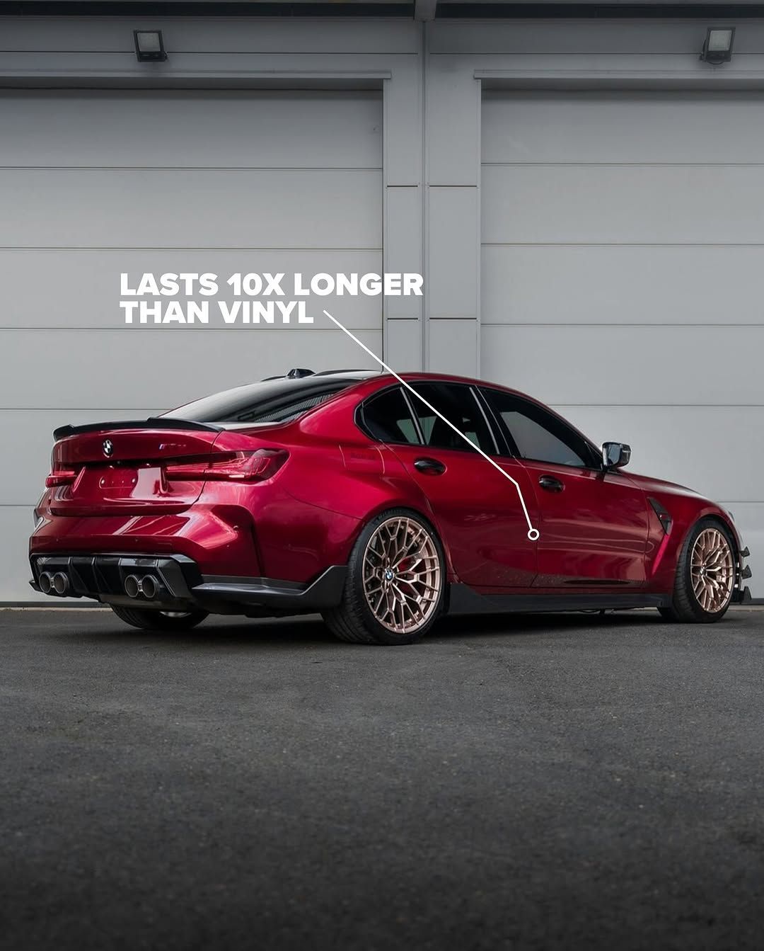 A red bmw m3 is parked in front of a garage door.