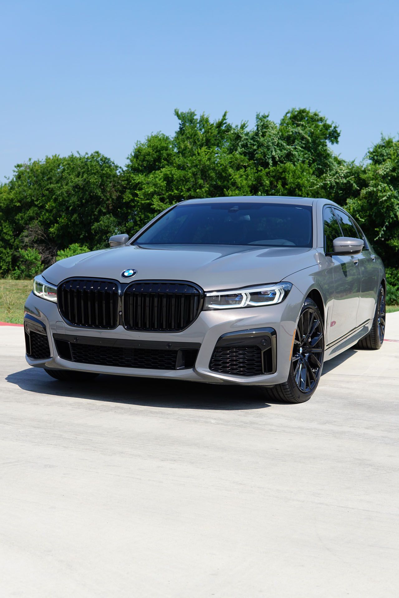 A silver bmw is parked on the side of the road.