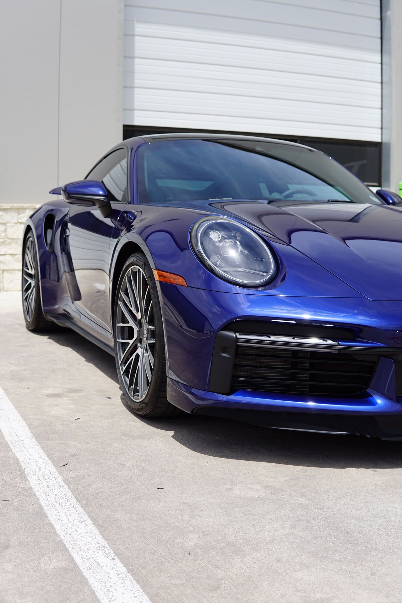 A blue porsche 911 turbo is parked in a parking lot.