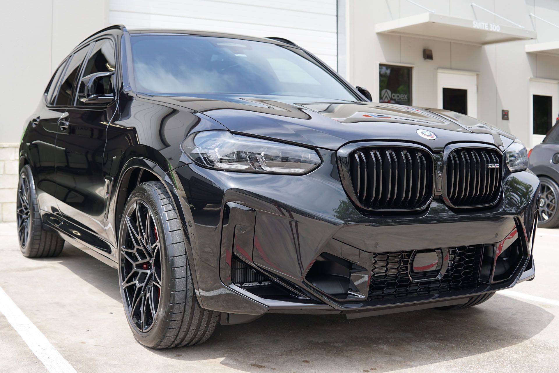 A black bmw x4 is parked in a parking lot in front of a building.