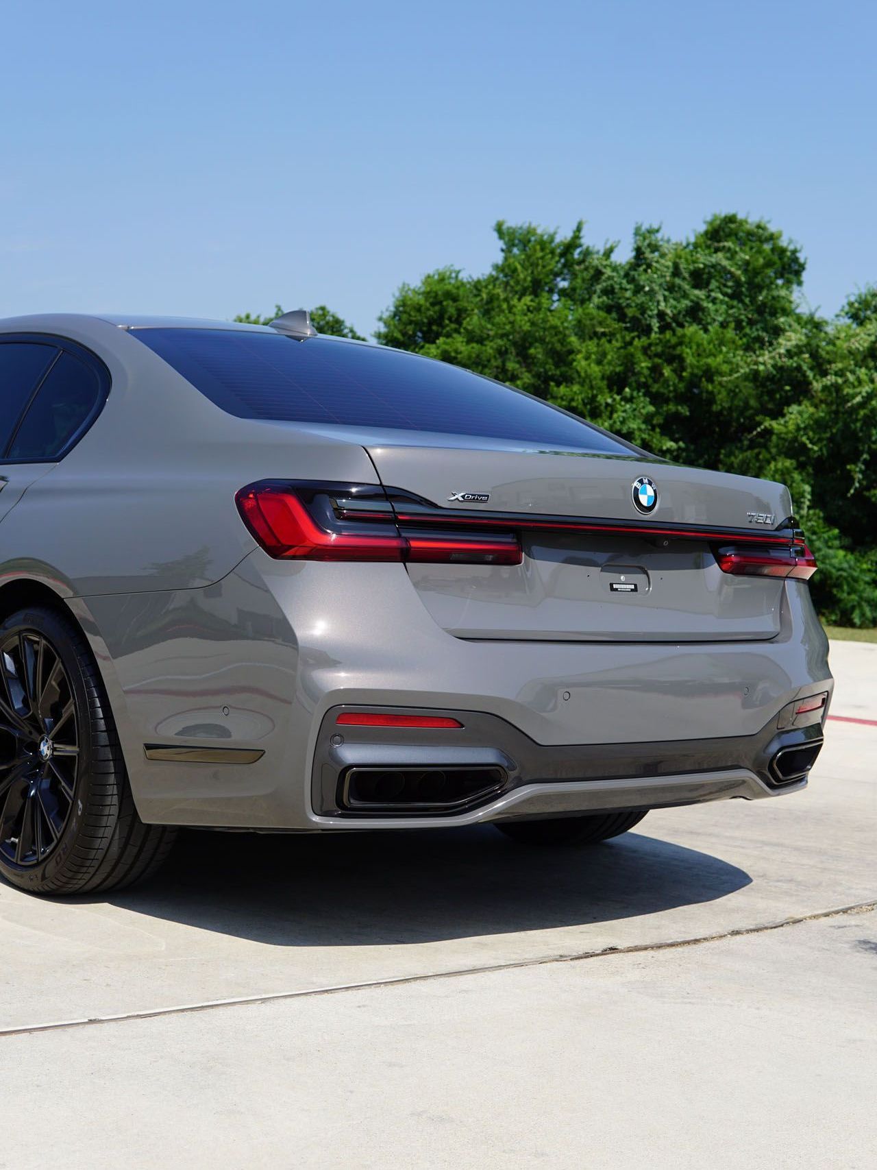 A silver bmw is parked on the side of the road.