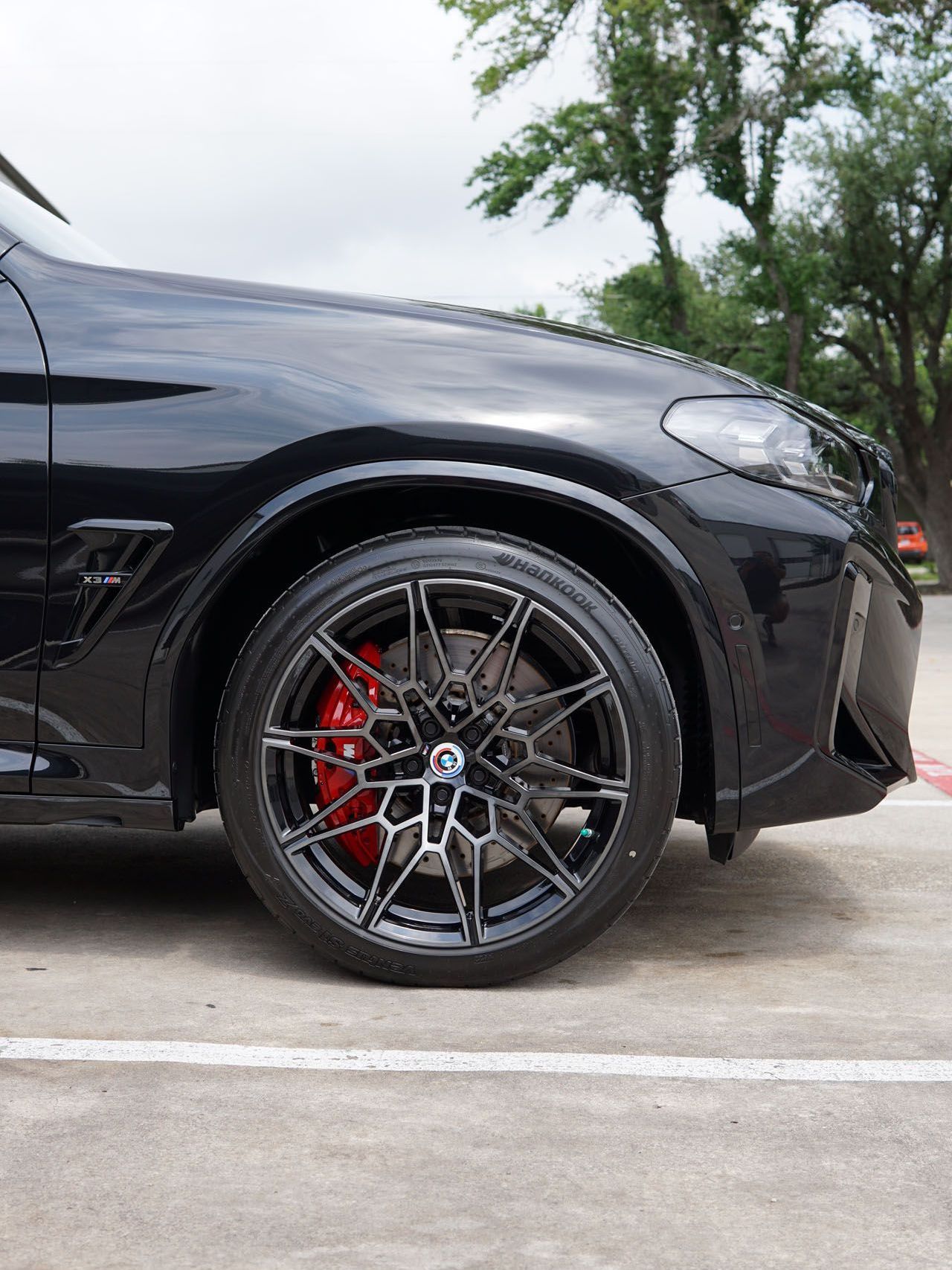 A black car with red brake calipers is parked in a parking lot.