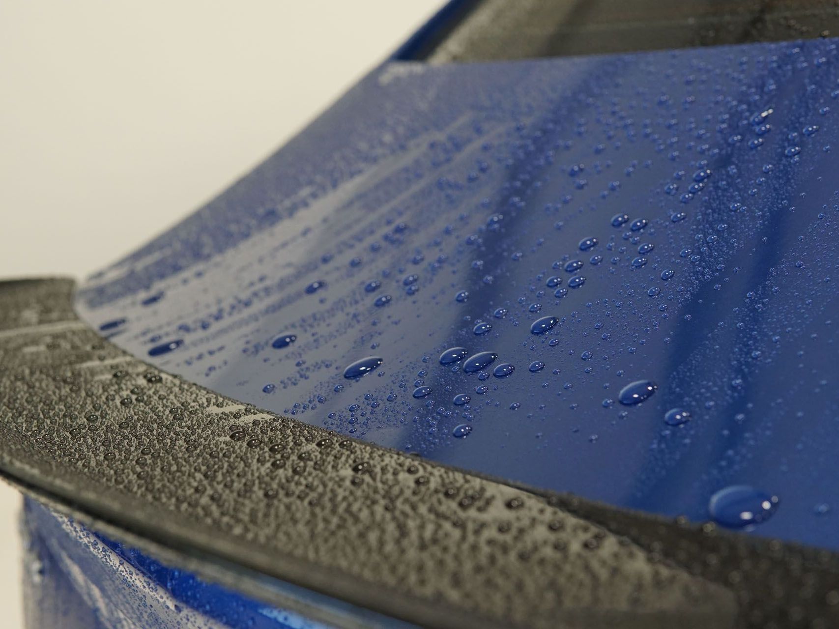 A close up of a blue car with water drops on it