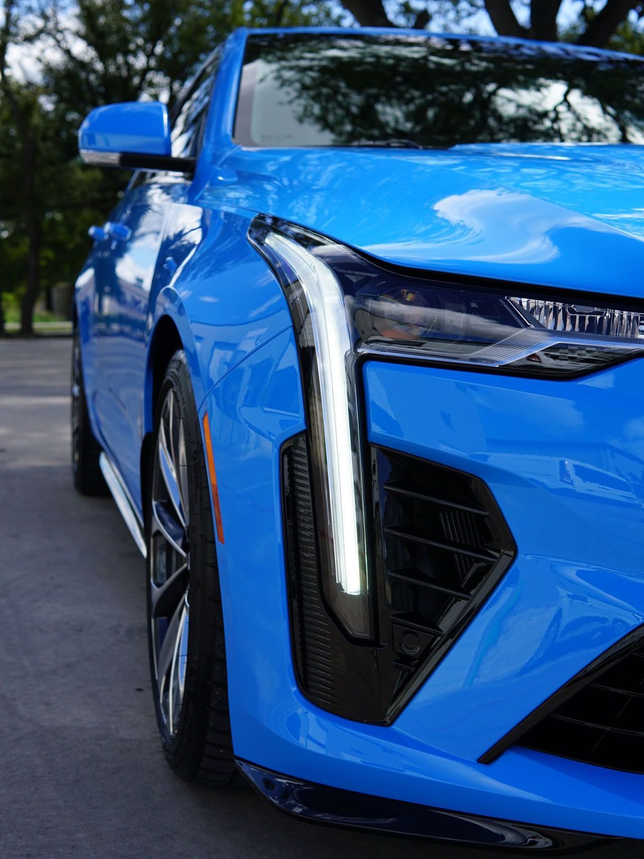 A close up of a blue car parked on the side of the road.