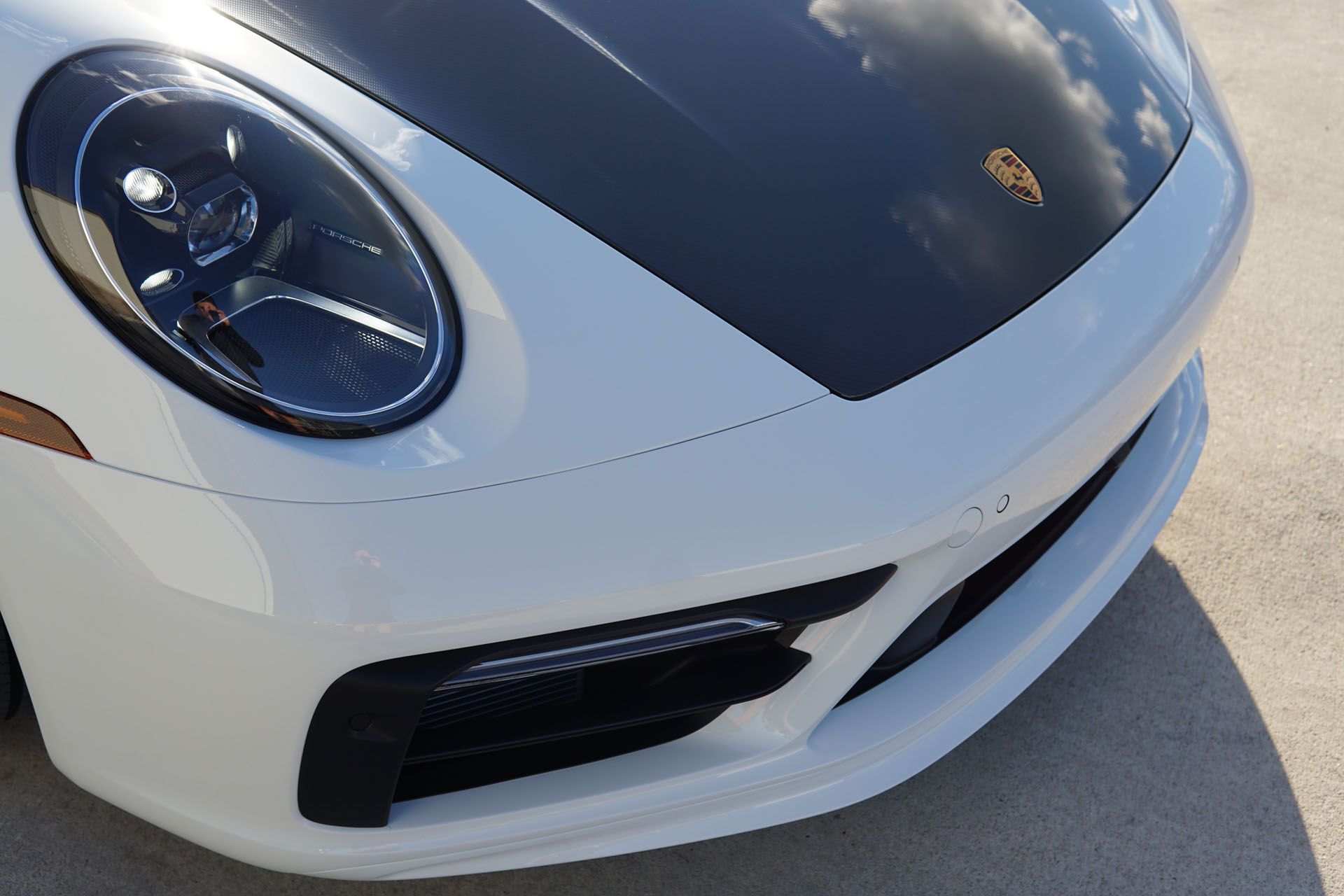 White Porsche car front with black hood and headlights.