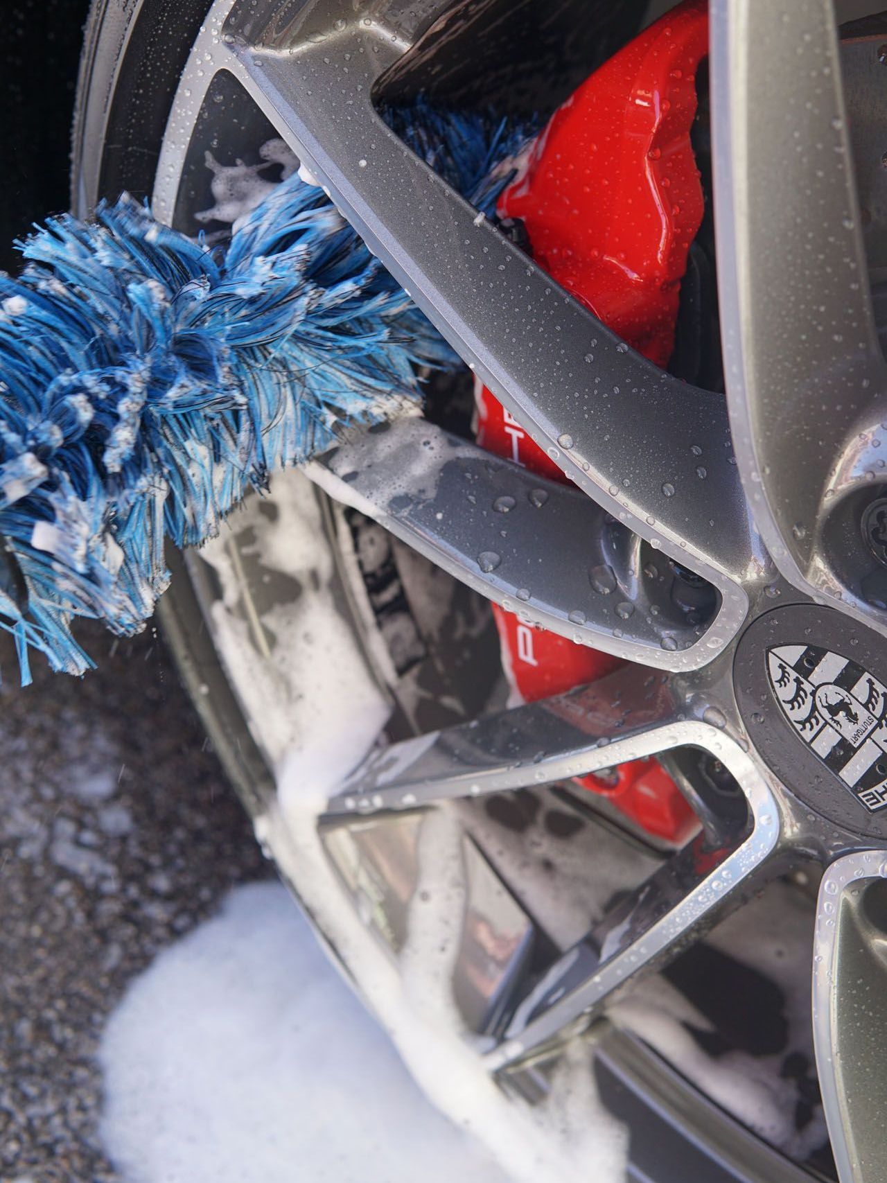 A close up of a car wheel being cleaned with a brush