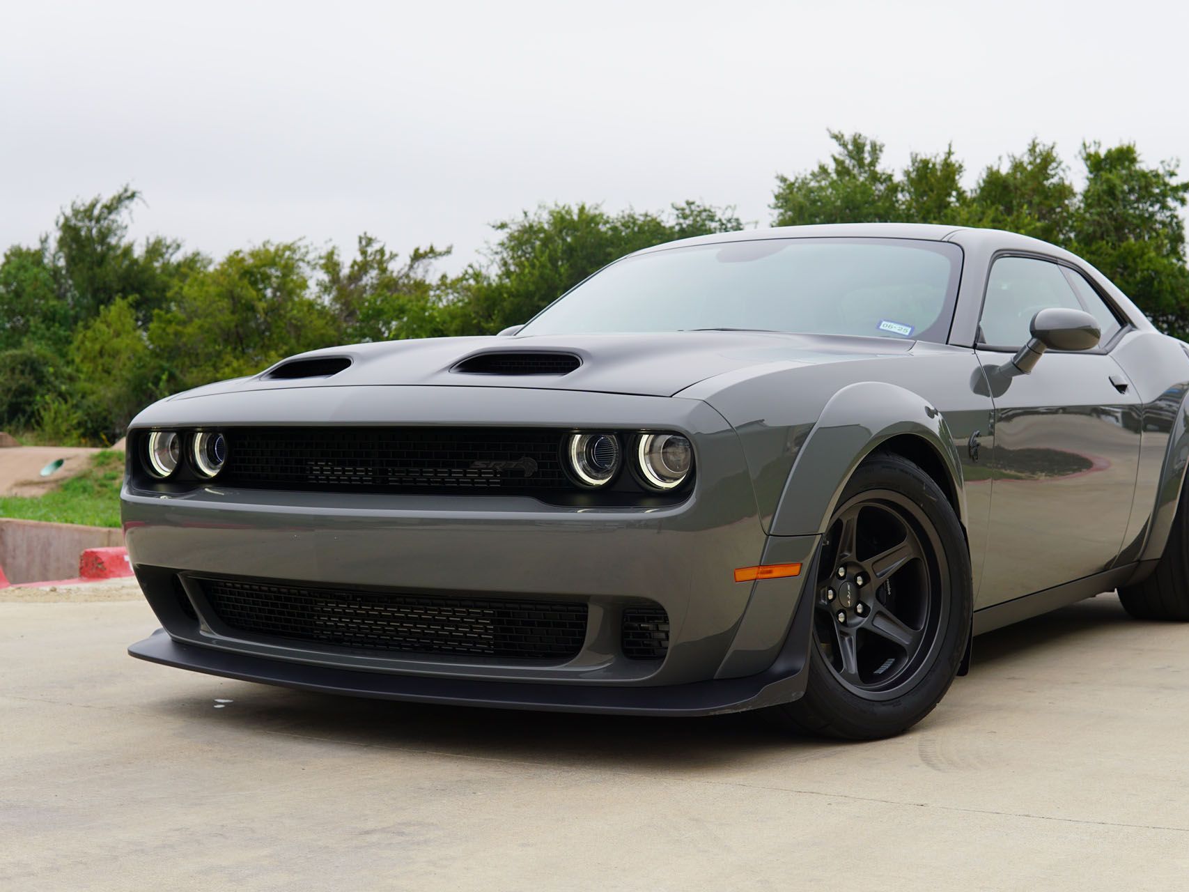 A gray dodge challenger is parked on the side of the road.