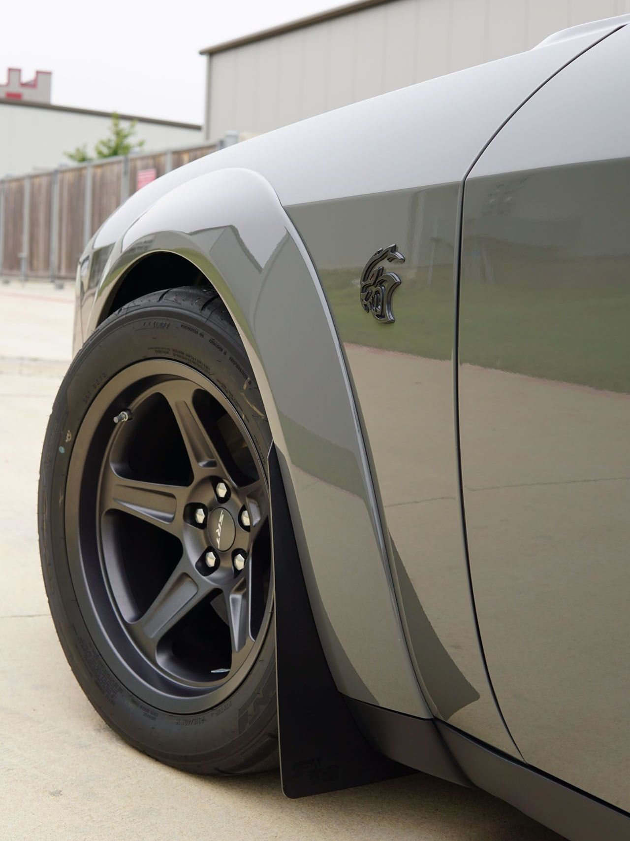 A gray dodge challenger is parked in front of a building