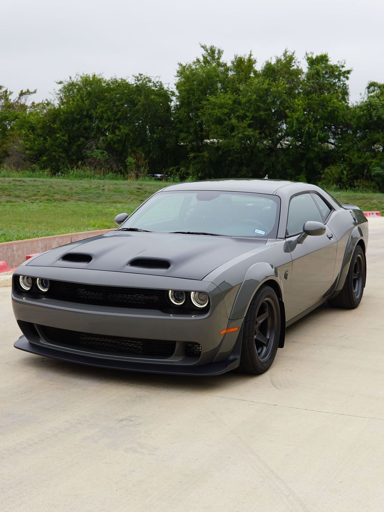 A gray dodge challenger is parked in a parking lot.