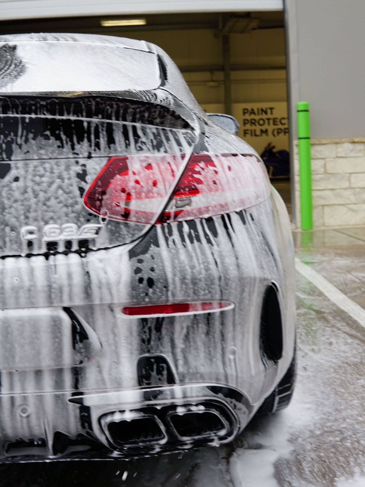 A green car with black wheels is parked in a garage.