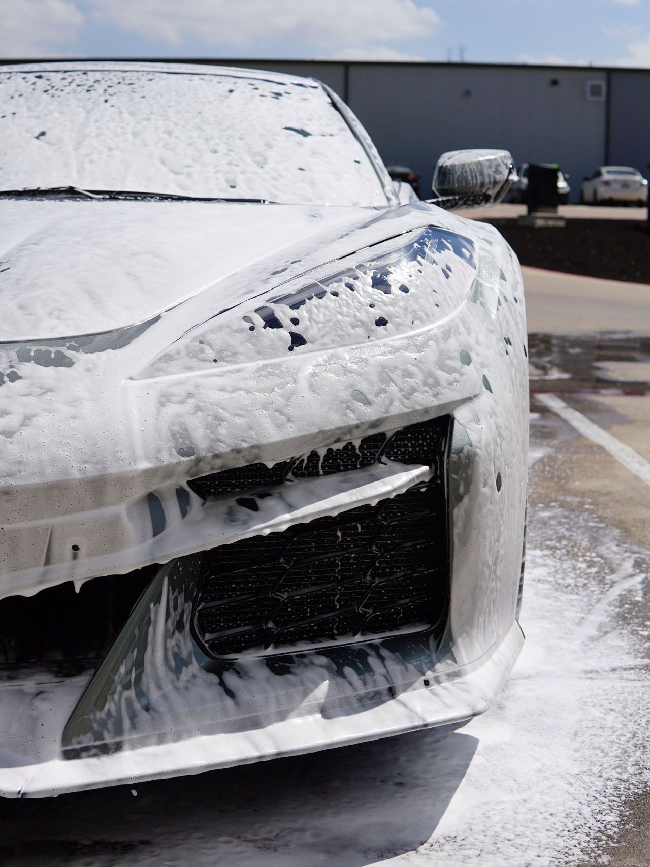 A car is covered in foam in a parking lot