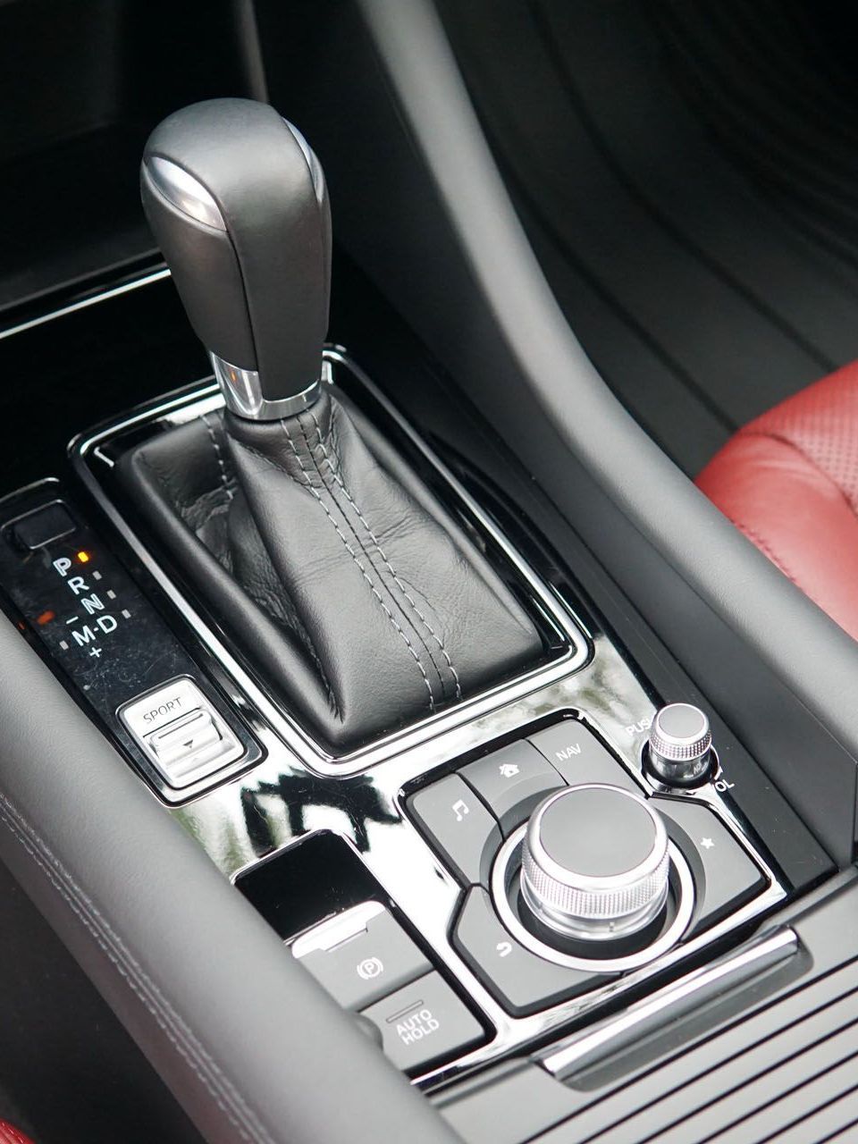 A close up of the center console of a car with a red seat.