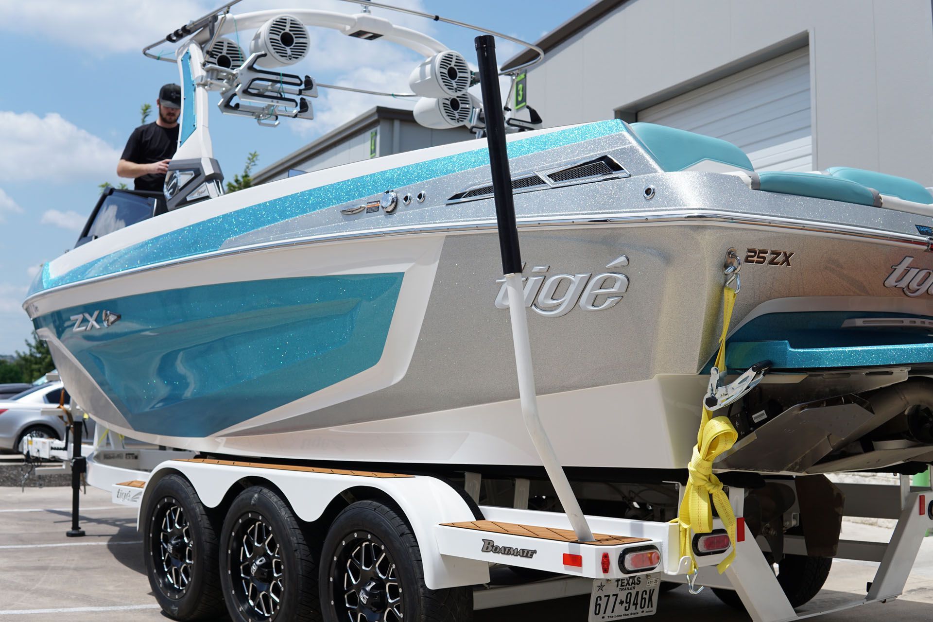 A man is standing next to a boat on a trailer.